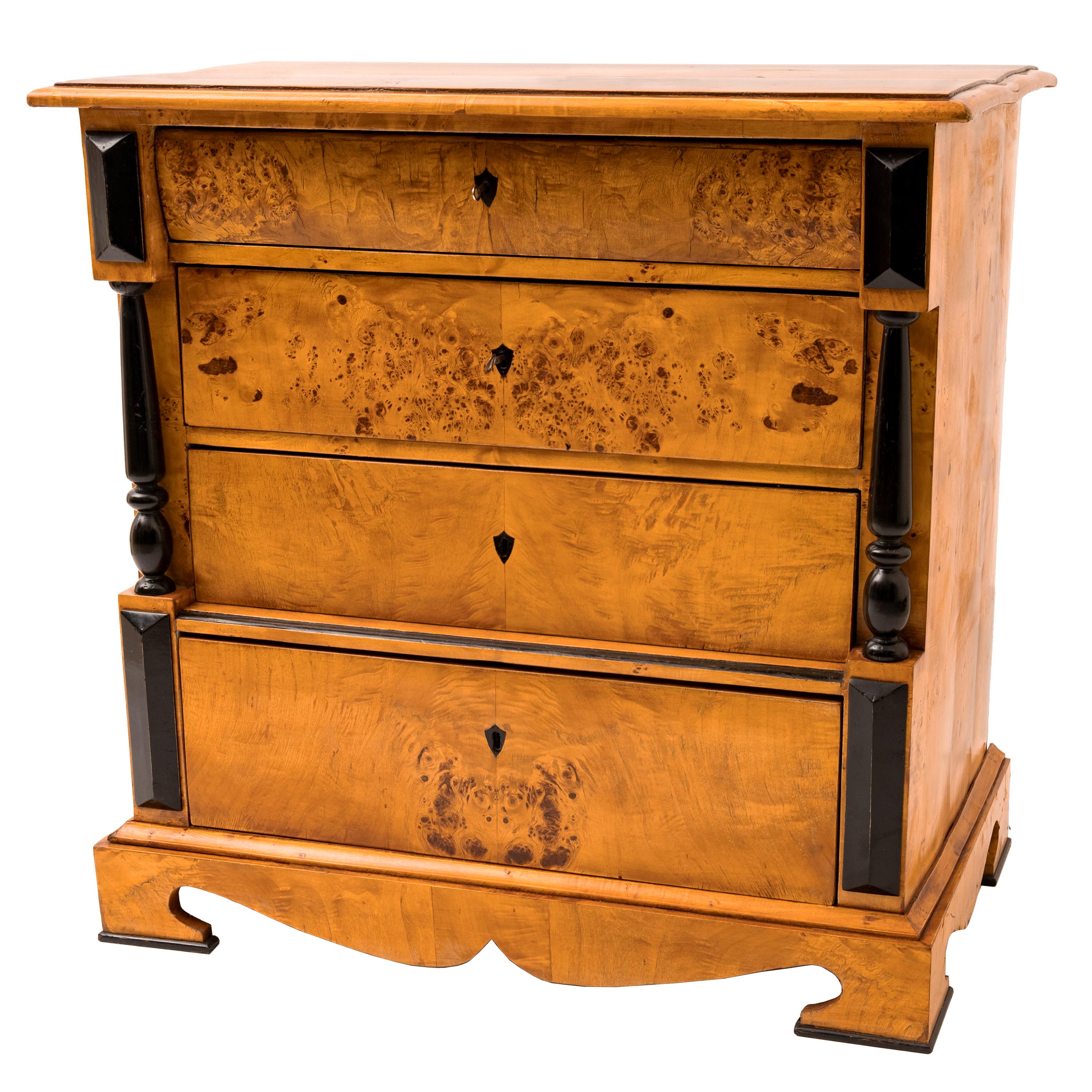 An elegant antique Swedish Biedermeier golden birch and burlwood chest of drawers, circa 1820.
The chest having a overhanging top with four graduated drawers below, the drawers are flanked with turned ebonized columns and having raised ebonized