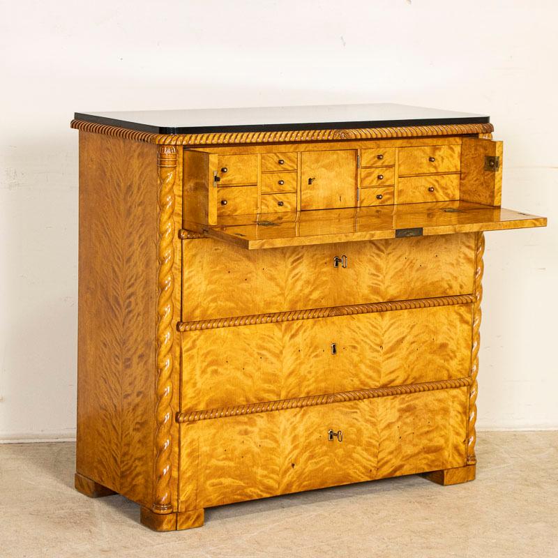 Antique Biedermeier birch secretary desk with three lowers drawers and a top drawer that folds down to reveal a fitted interior with multiple small drawers. This stunning chest of drawers is made of birch wood with shellac finish that brings the