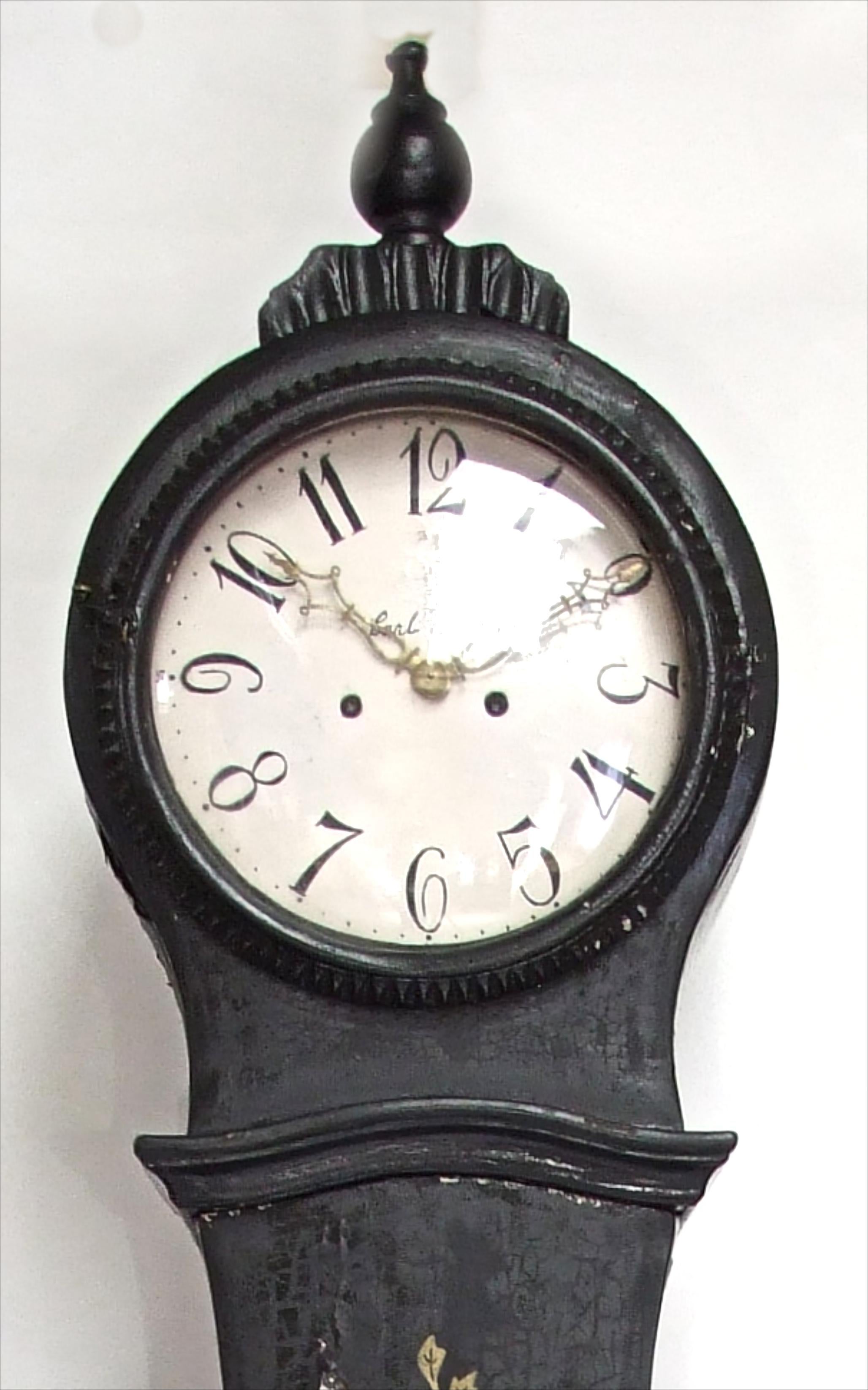 Antique Swedish Mora clock from early 1800s in original black paint with hand painted gold designs and decorative feet and a good face

The clock body paint has the usual wood movement and paint distressing found in clocks of this age. 

We will