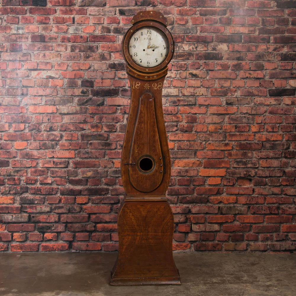 This grandfather clock was painted in the very traditional earth-tone style of the 1800s in Sweden. Unique to this clock dated 1828, is the original paint in remarkable condition and a framed photograph of the owner with this clock in his home,