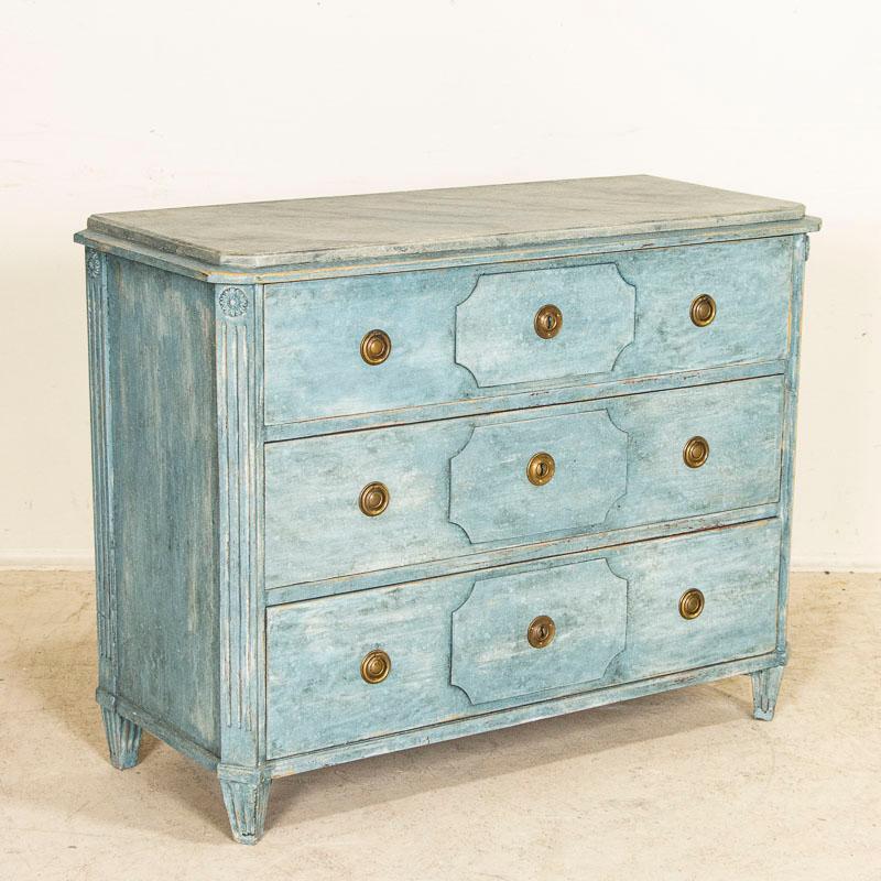 This lovely blue painted chest of drawer has the simple yet elegant lines that reveal its Swedish country style. The carving along the side columns were a traditional style motif reflecting the craftsmanship of the era, while the raised panel in the