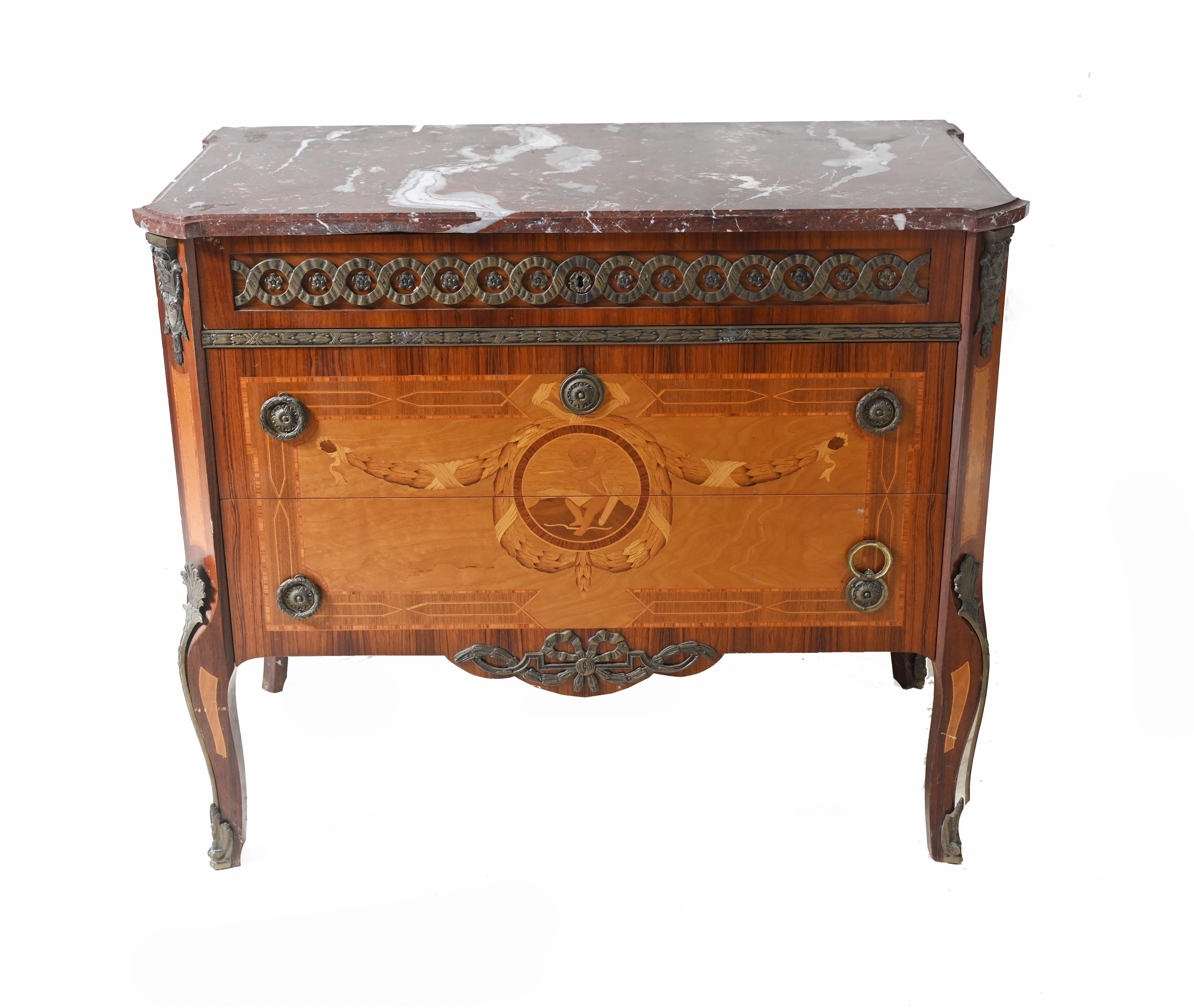 Vous voyez ici une commode suédoise raffinée avec des incrustations complexes.
Circa 1920
Le plateau rectangulaire est réalisé en marbre rouge richement veiné et strié de blanc, avec un bord moulé.
Le tiroir supérieur est orné d'un motif géométrique