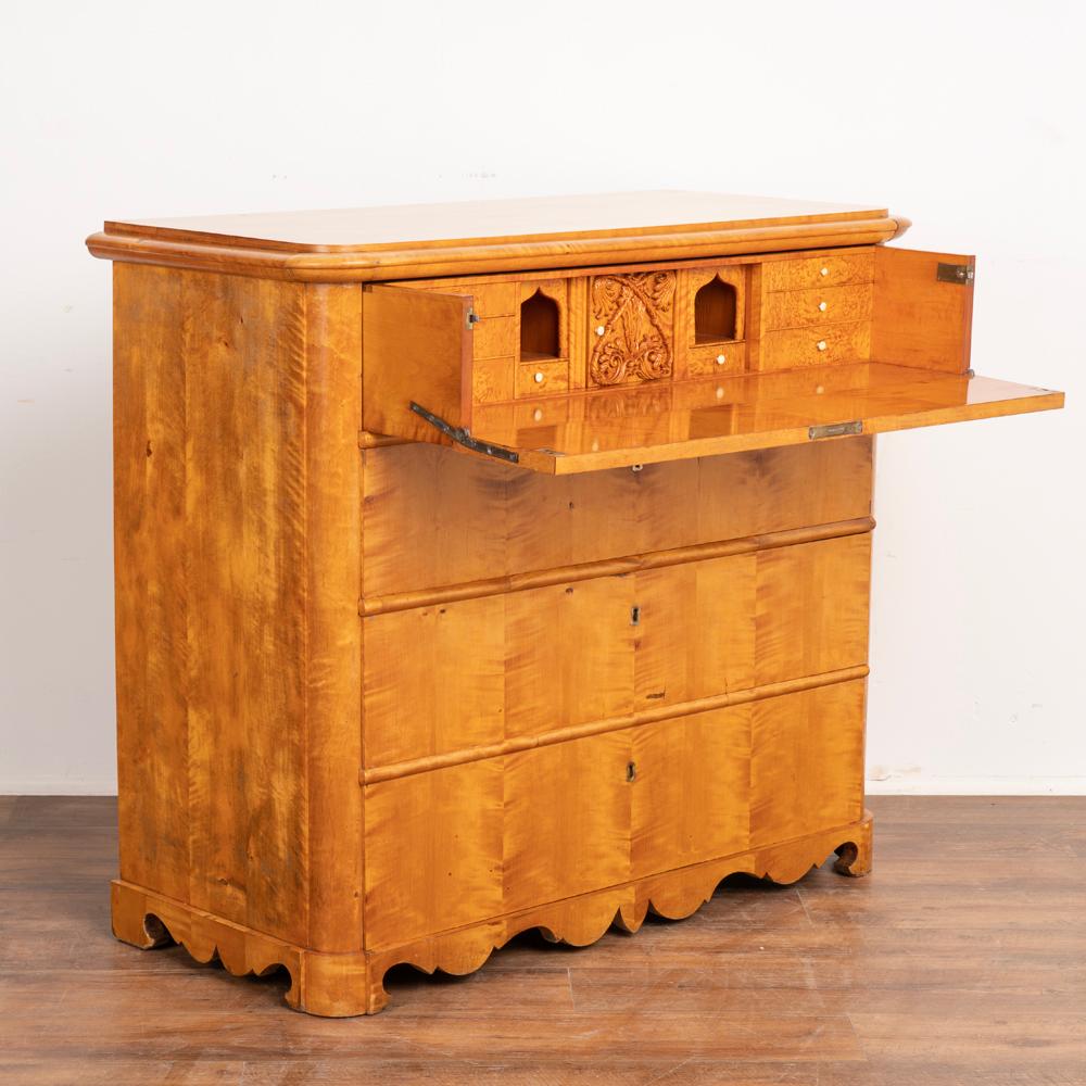 Birch Swedish country biedermeier chest of drawers that also serves as a secretary or bureau.
Upper cabinet interior holds petite drawers and cubbies typical of a secretary, while the central square door has hand-carved flourishes adding to the