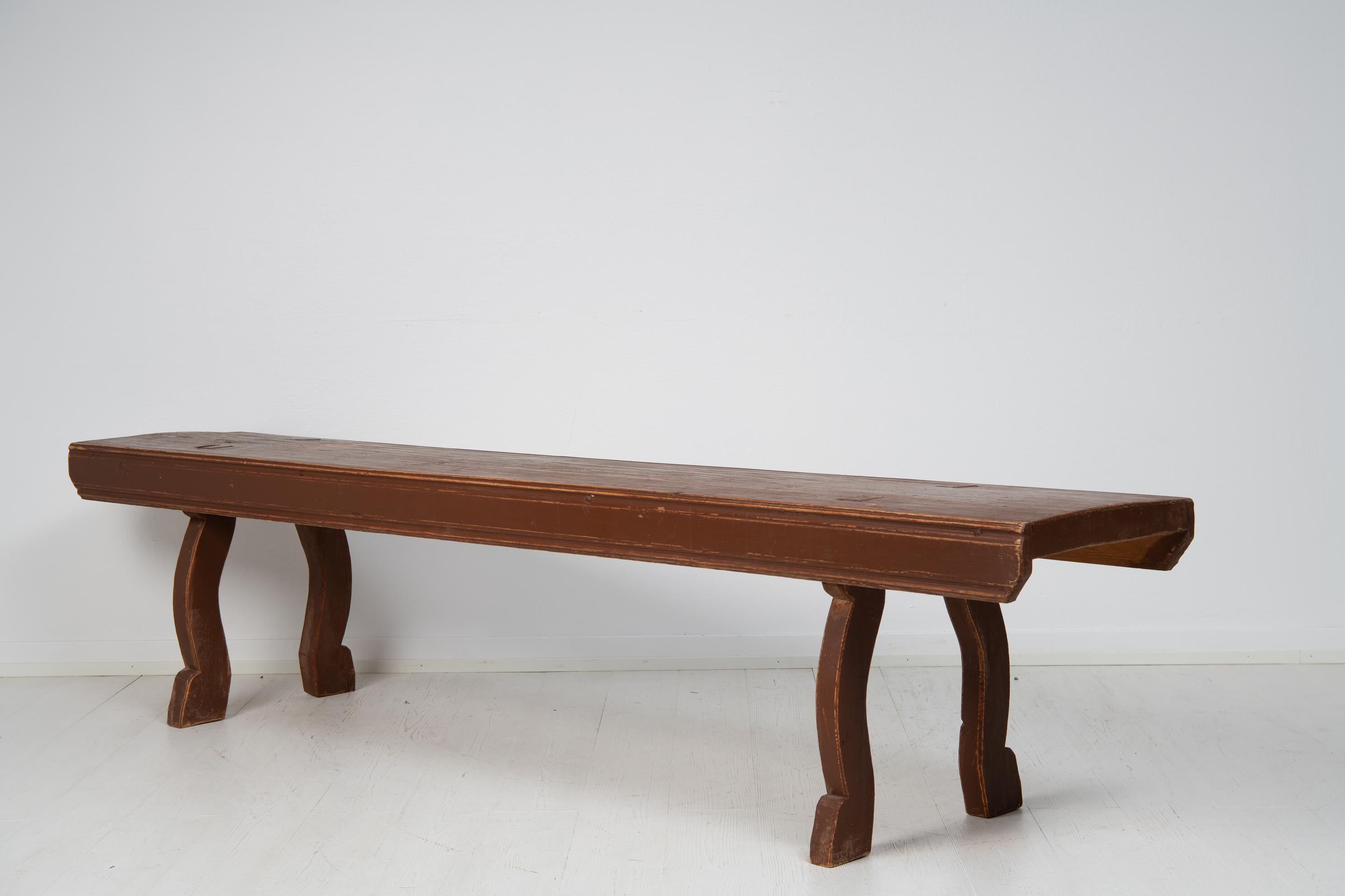 Antique Swedish country house bench made in solid pine during the mid 19th century, around 1850. The legs are curved with a simple hand-carved detail above the foot. The side of the bench has an extra profiling, or small flutes, running along the
