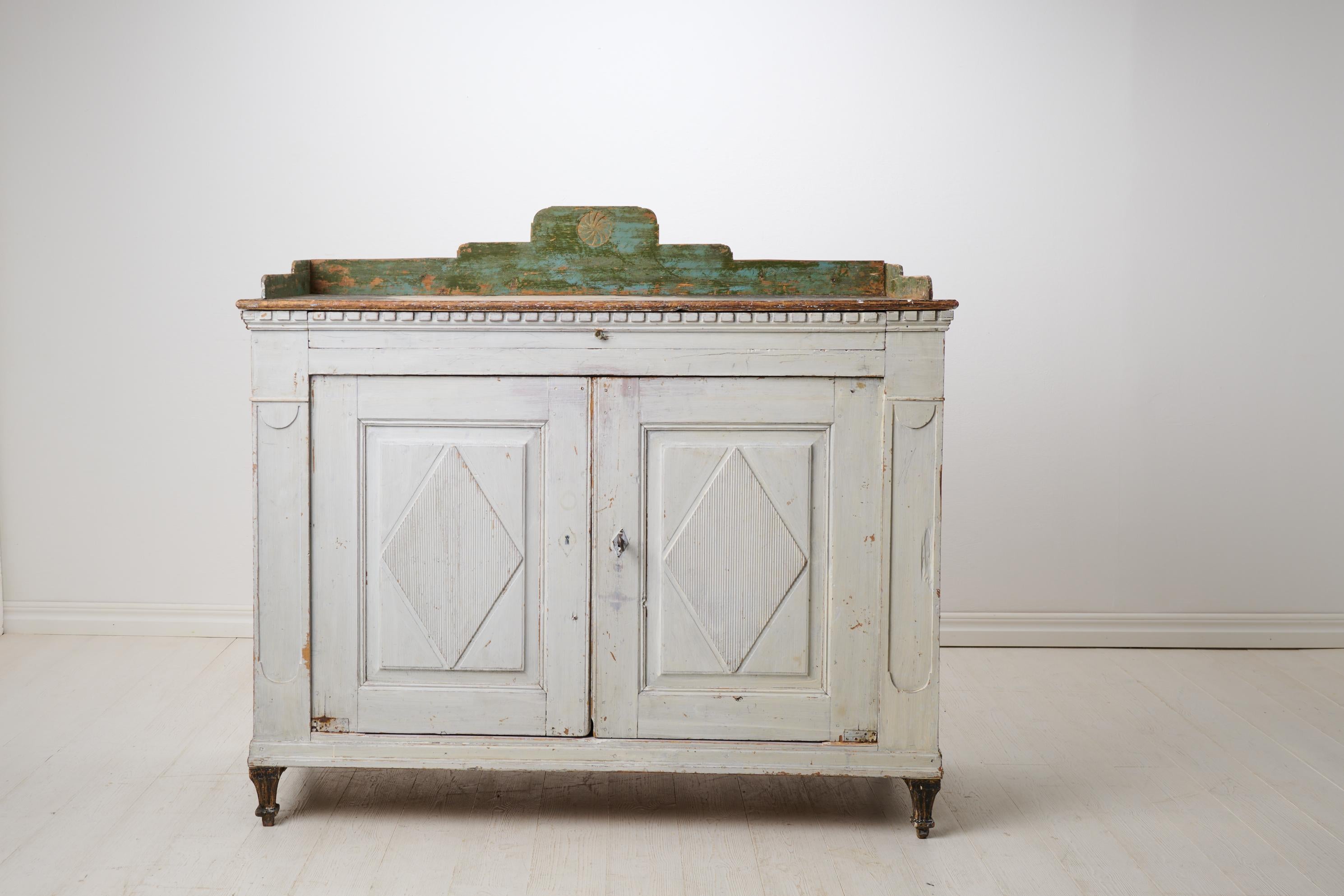 Antique Swedish country sideboard in gustavian style. This country house furniture is made by hand in solid pine in northern Sweden around 1820. The sideboard has old historic paint which shows the history and patina of the piece. Time-typical