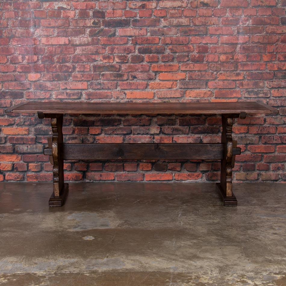 Your eye is immediately drawn to the rich walnut patina on this Swedish farm table, beautifully distressed from decades of use. Constructed of solid pine with a trestle base, the broad stretcher and wide platform feet give this table strength and