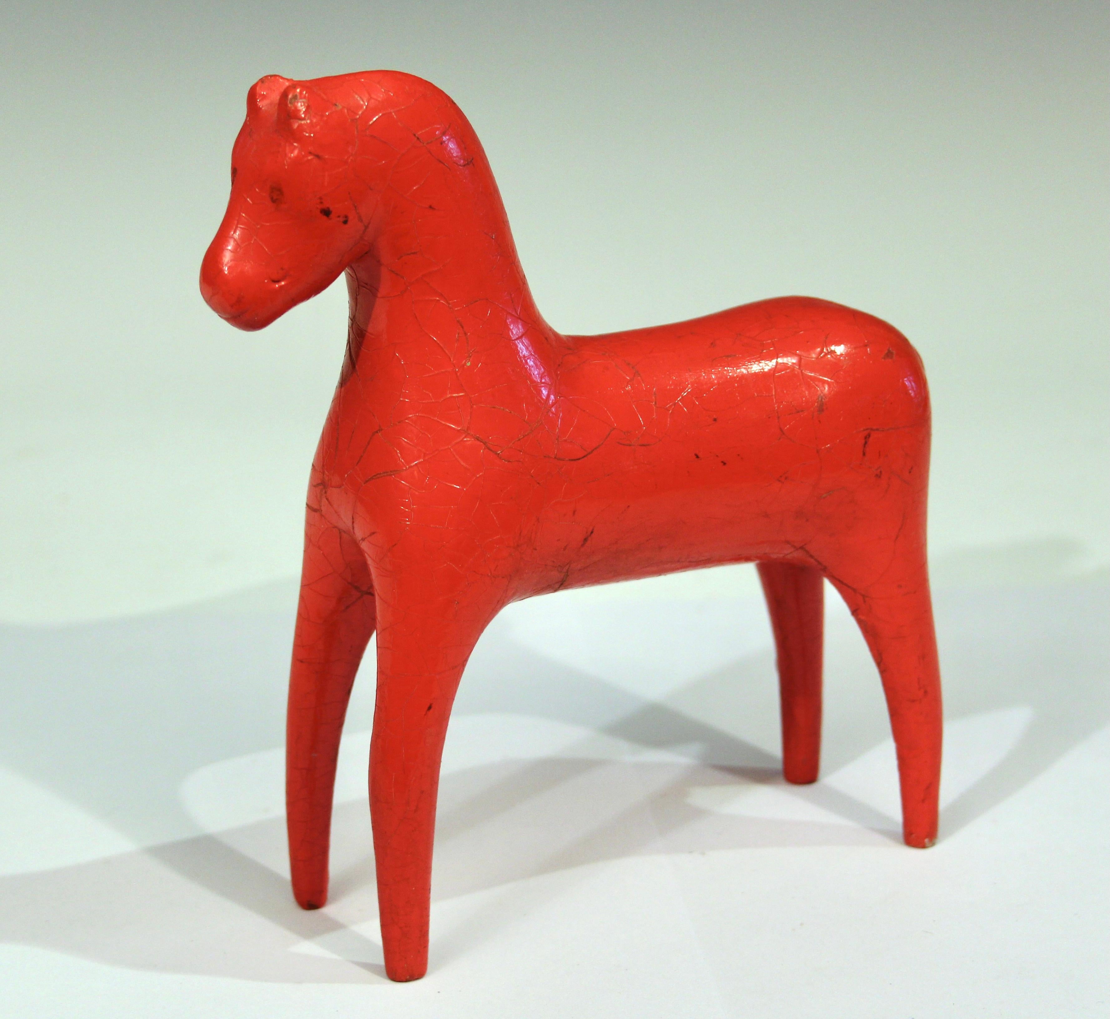 Antique Swedish Dala horse in bright red paint, circa 19th/early 20th century. Beautifully carved with slender legs and graceful form with little ears, a cropped tail, and faintly defined grin. With heavy red oil paint that has crackled over the
