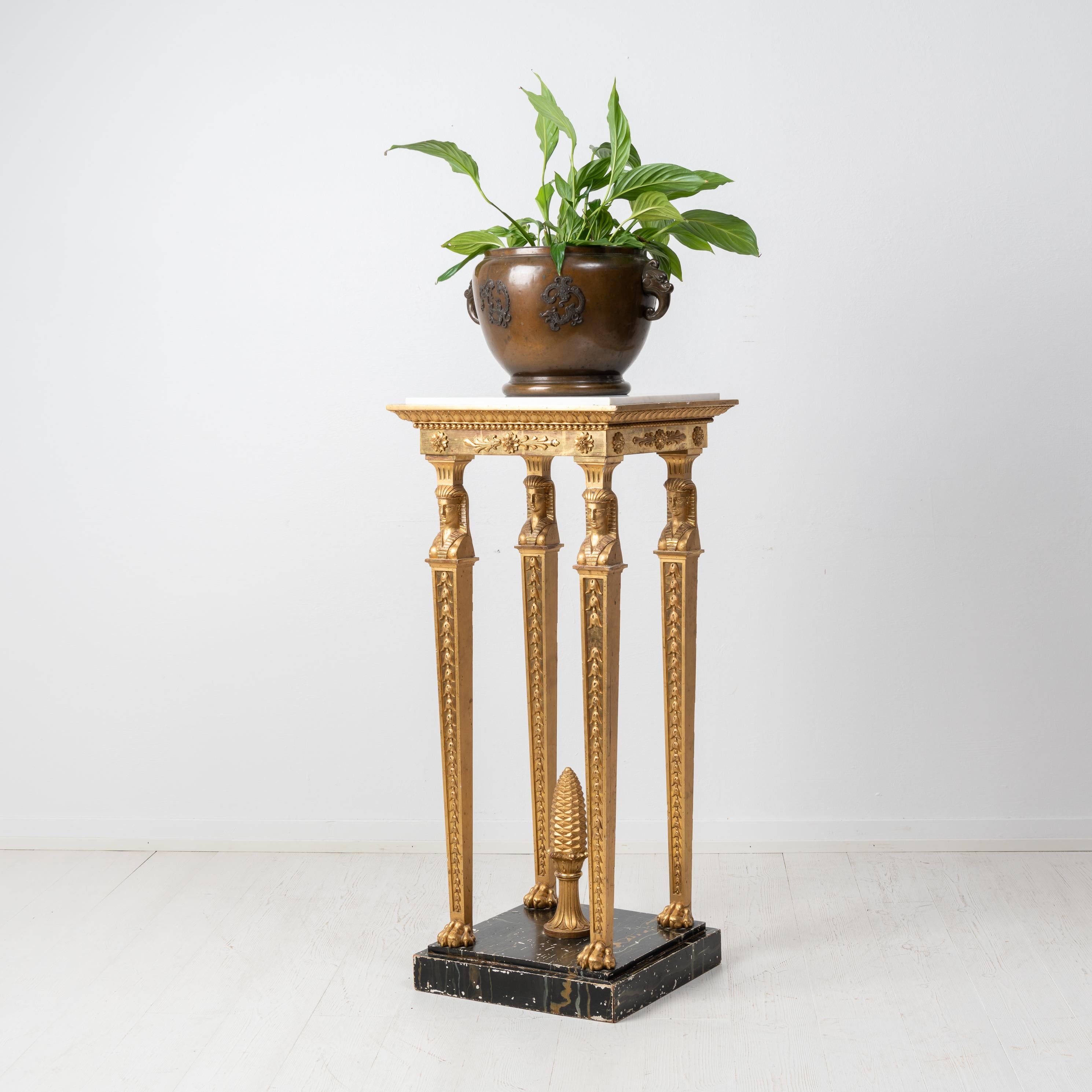 Gilded empire pedestal or geridong from the mid 1800s, around 1840. The pedestal is from Sweden and is gilded with a white marble top in Carrara marble. The pedestal is in good vintage condition consistent with age with some smaller traces of use.