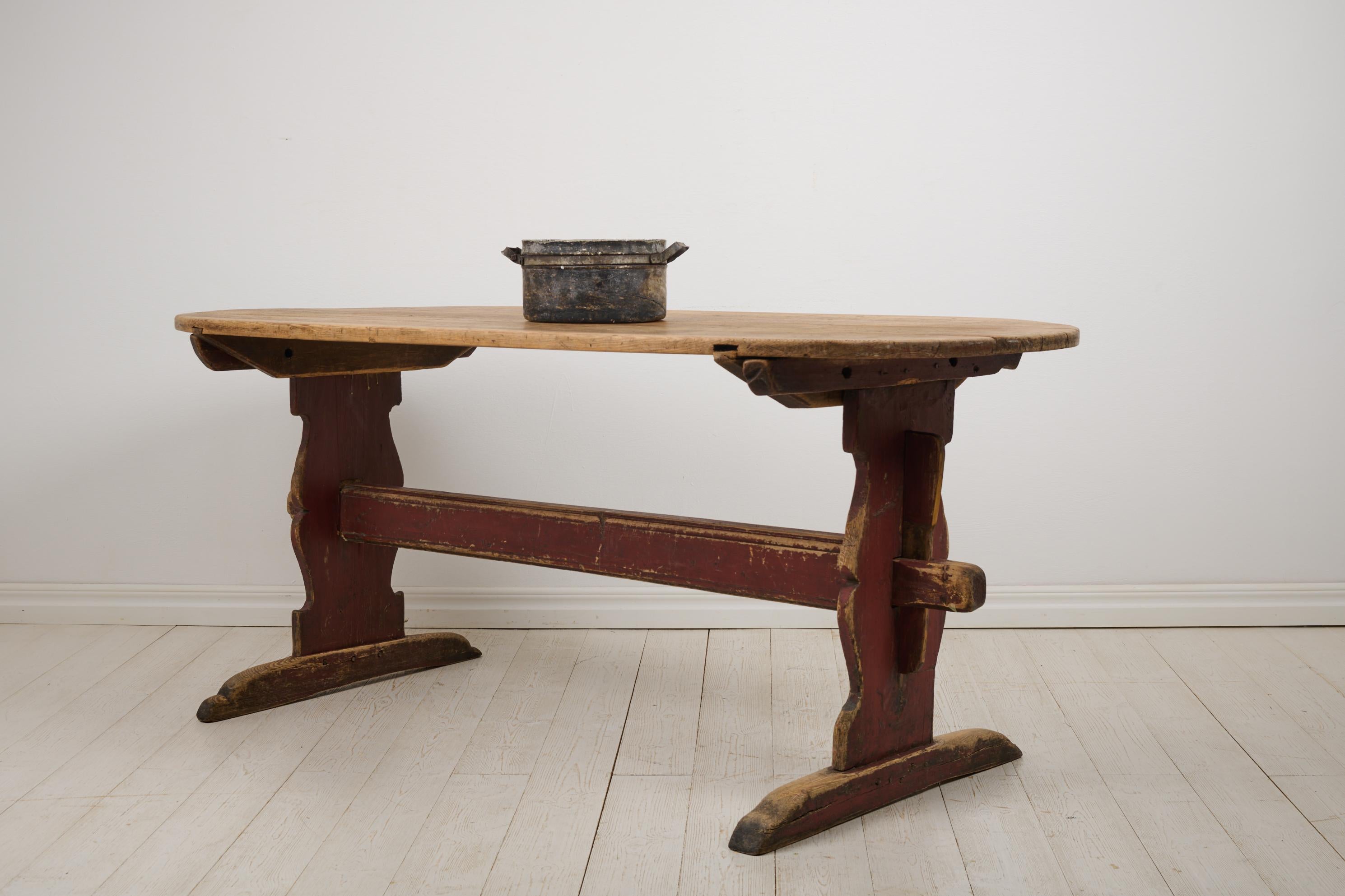 Antique Swedish dining table in folk art from the early 1800s. The table is a so called trestle table with a heavy table top on a sturdy leg frame. Made in northern Sweden around 1820. Original condition with an original wood bare table top – made
