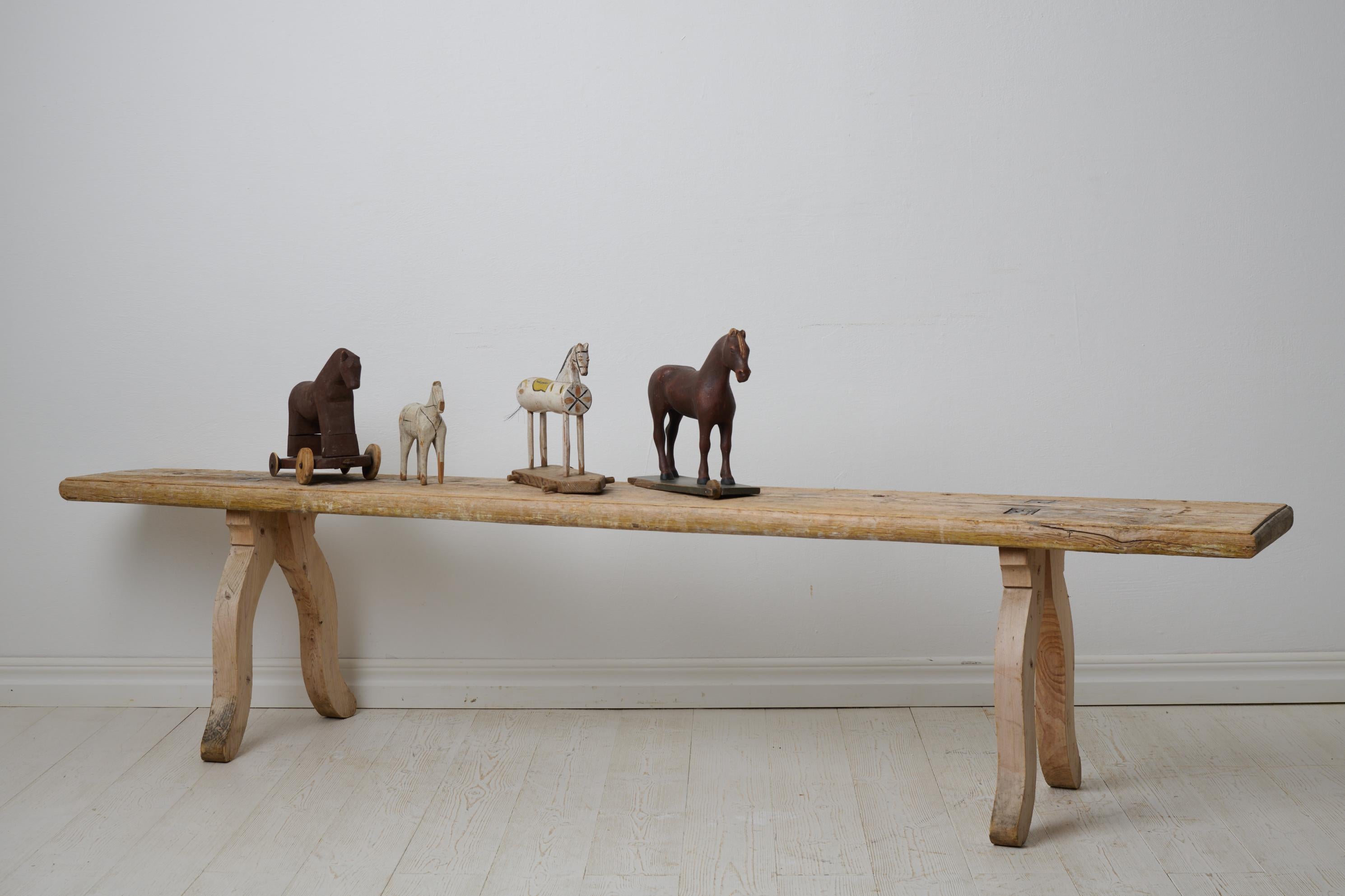 Antique folk art bench from Sweden made around 1820. The bench is made by hand in solid pine and has never been painted. Rare primitive folk art furniture. Unusually curved, rococo legs. Small bevelled edge around the seat itself. Traces and marks,