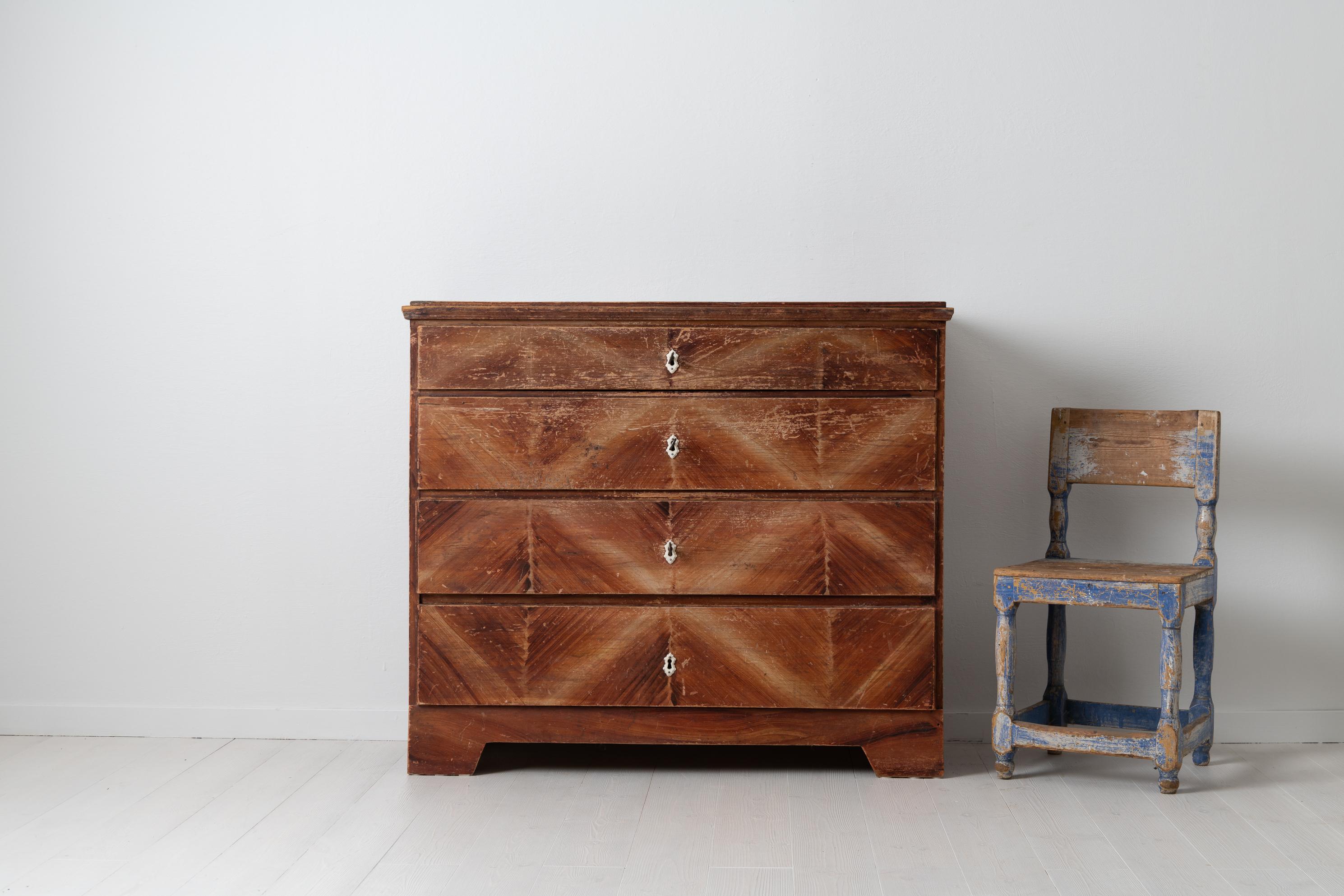Chest of drawers in folk art. The chest is from northern Sweden and made in pine during the mid-1800s. Four drawers with original locks and key in working condition. The chest has unusual decorative paint on the drawers, almost a geometric pattern.