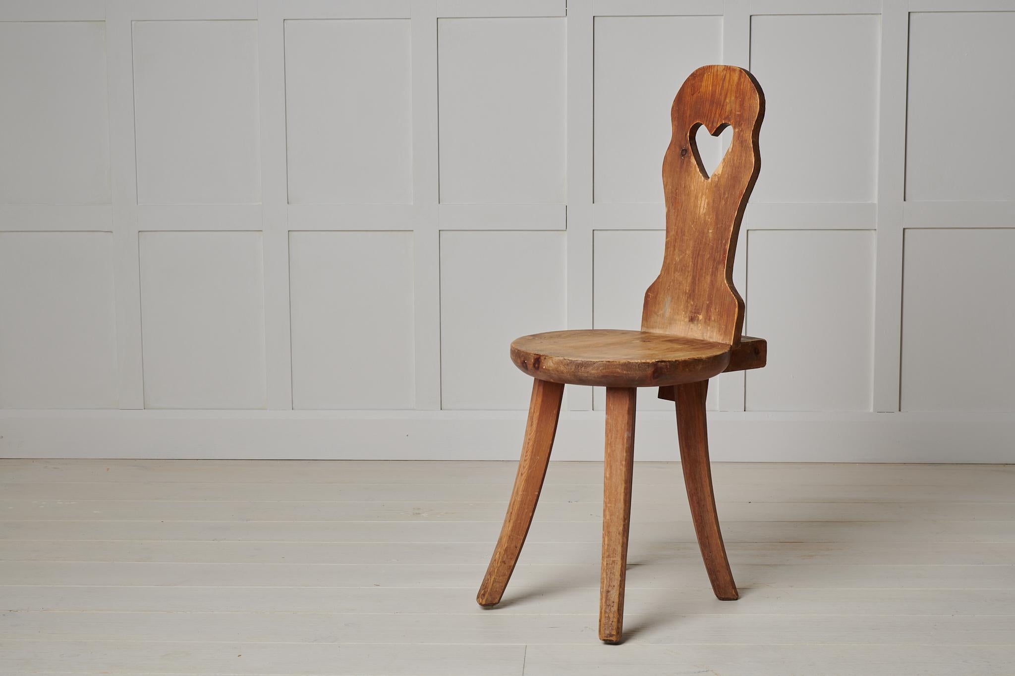 Schwedischer Volkskunststuhl aus den späten 1800er Jahren. Der Stuhl ist handgefertigt aus Kiefernholz mit einem ausgeschnittenen Herz auf der Rückenlehne. Der Stuhl wurde nie gestrichen, so dass das Kiefernholz mit der Zeit und dem Gebrauch im