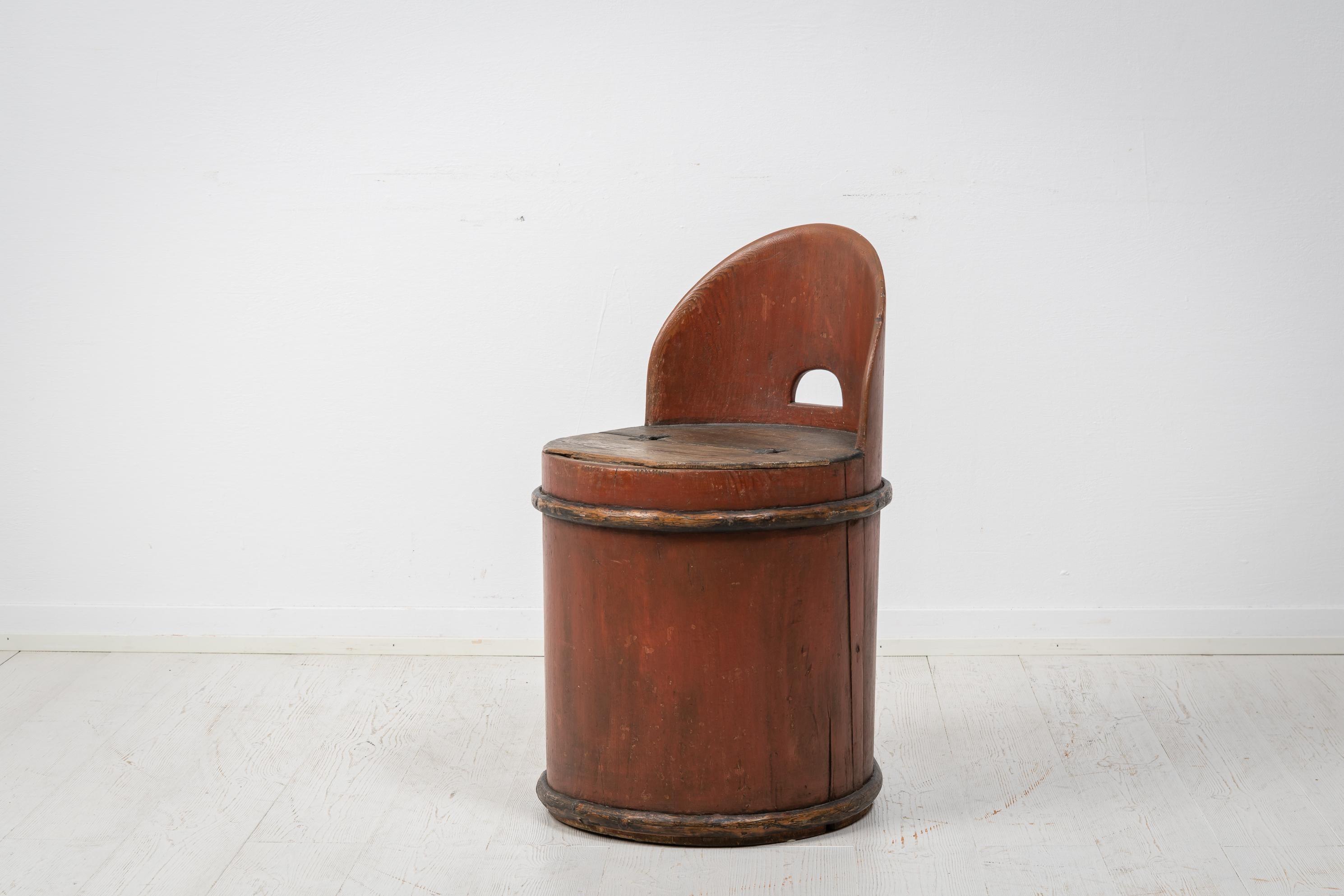 Antique Swedish stump chair in folk art. The chair has a round shape and is made from a hollowed pine tree stump. The chair is in untouched condition with old paint and distress and patina after use. An extra detail is the storage space underneath