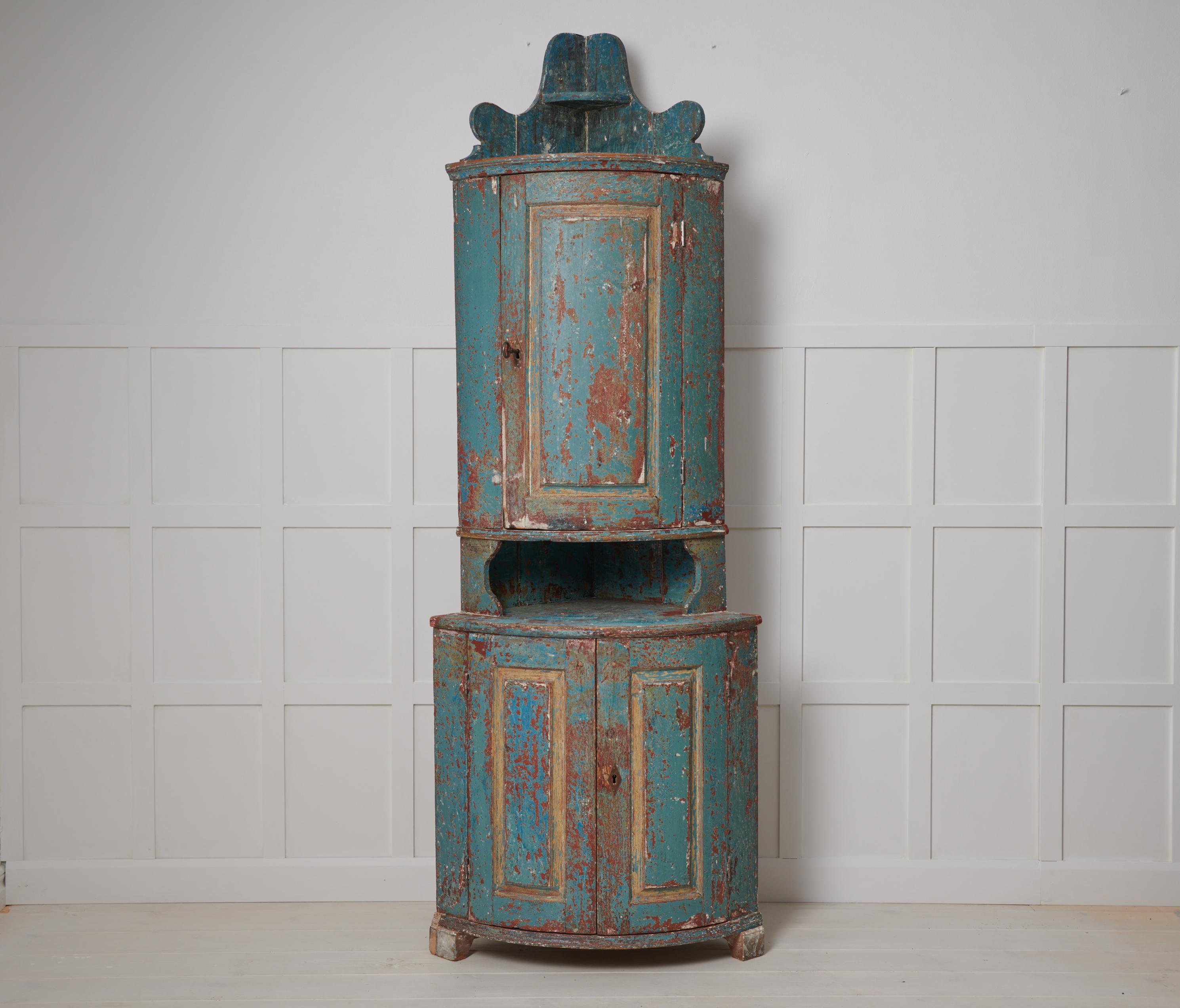 Antique Swedish corner cabinet. The cabinet is a genuine Swedish country house furniture from the early 1800s. Old historic paint with a rustic surface and genuine patina and character. The cabinet has working locks and keys. The sides of the lower