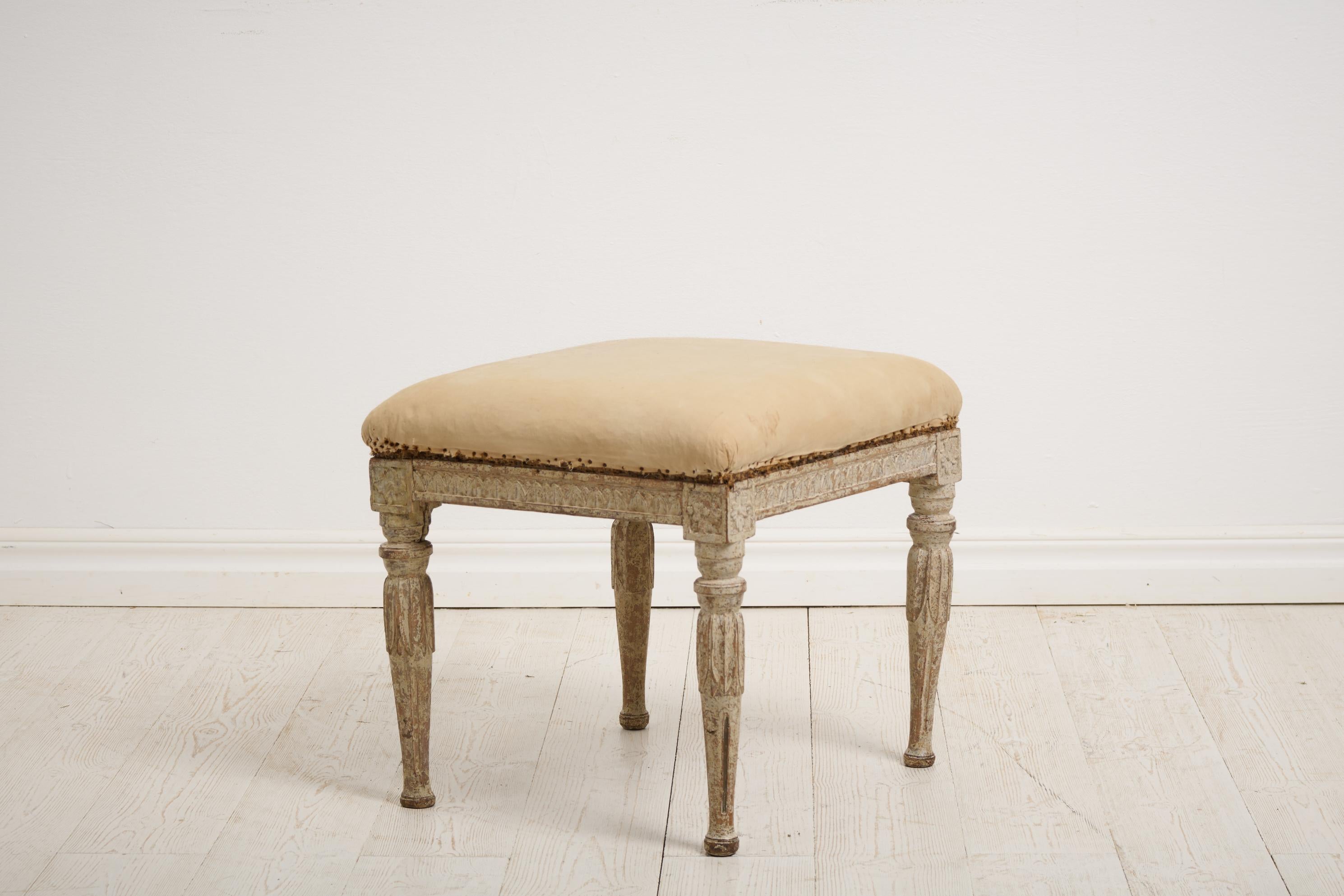 Genuine antique foot stool from the Swedish gustavian period around 1770 to 1780. This Swedish antique has classic carved wooden decor on the legs and sides. Original paint from the late 1700s with distress and patina, the wood shines through in