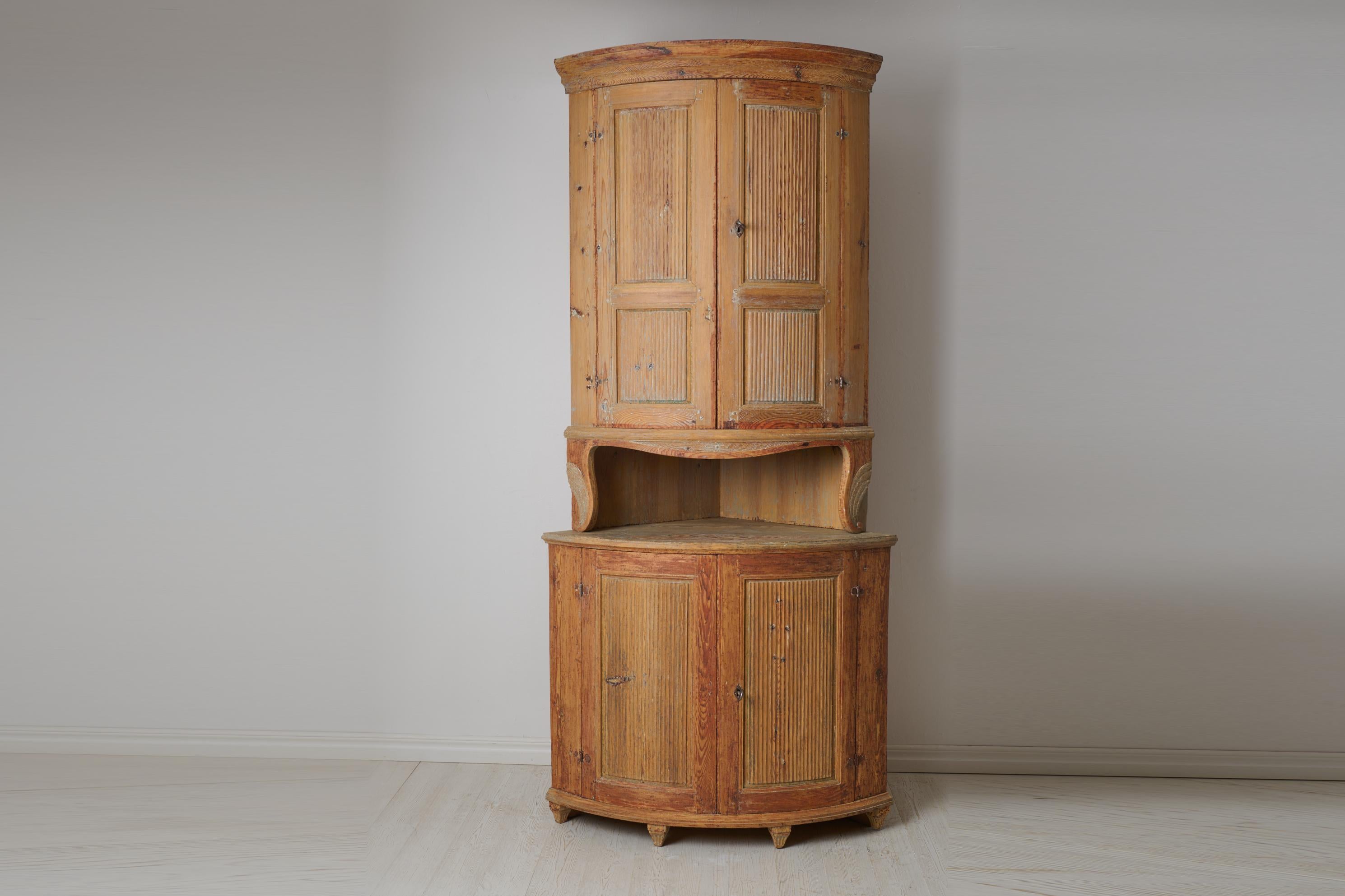 Meuble d'angle ancien de style gustavien fabriqué à la main en pin massif. Le meuble est un authentique meuble de campagne suédois composé de deux parties. Il présente un style gustavien classique, un modèle droit avec une façade arrondie et des