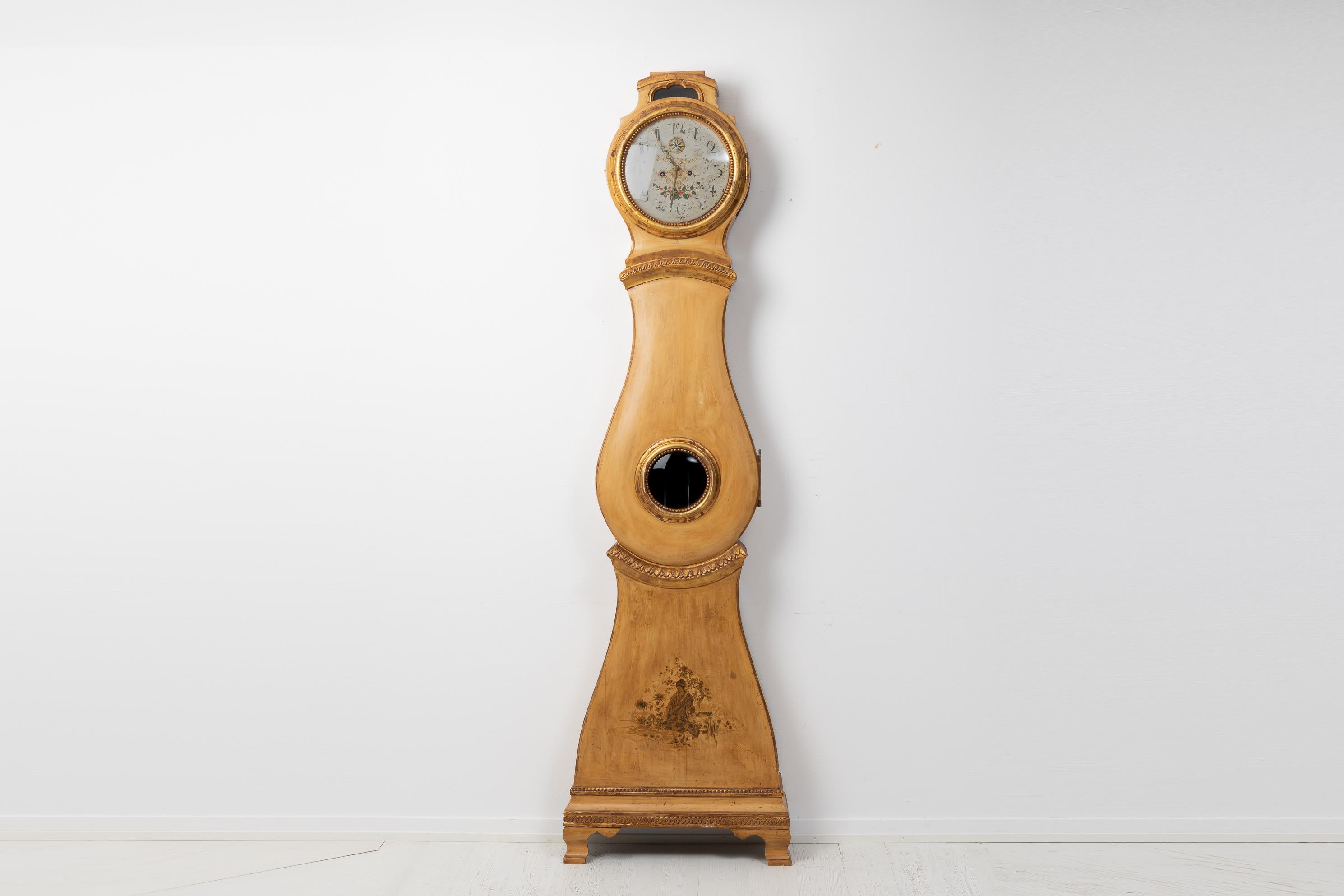 Antike gustavianische Standuhr aus bemalter Kiefer aus Schweden. Die Uhr hat ein handgeschnitztes Dekor aus Holz mit älterer Farbe aus den späten 1800er Jahren. Die Farbe ist im Laufe der Zeit leicht in Mitleidenschaft gezogen worden, was der Uhr