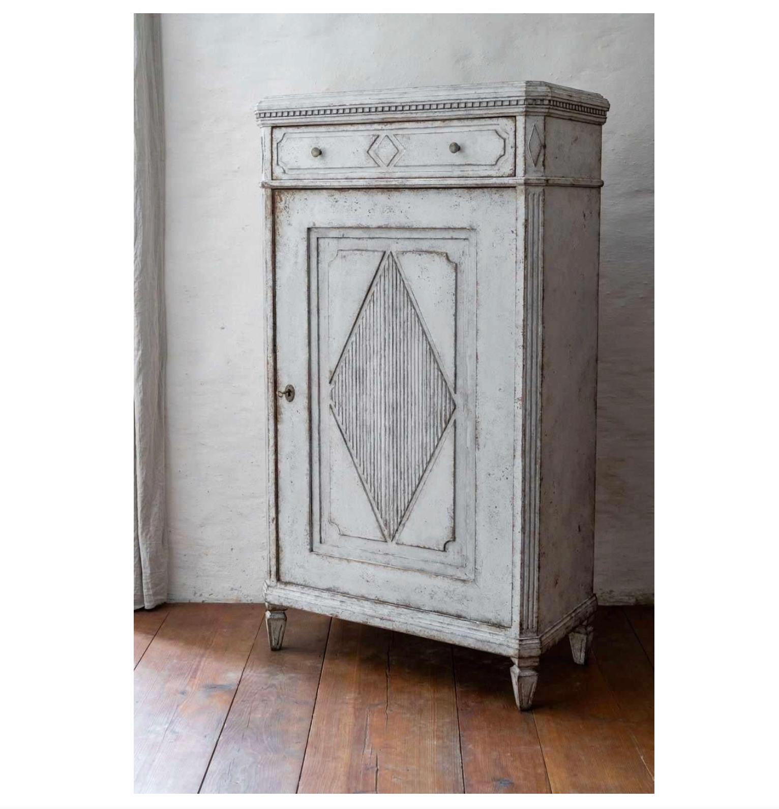 Circa 1860 antique Swedish Gustavian White painted Sideboard Buffet commode in gustavian style with classic Gustavian diamond ribbing detail on the door front and on the drawer.

It has pyramid feet, hound tooth top edge and  internal shelves with a