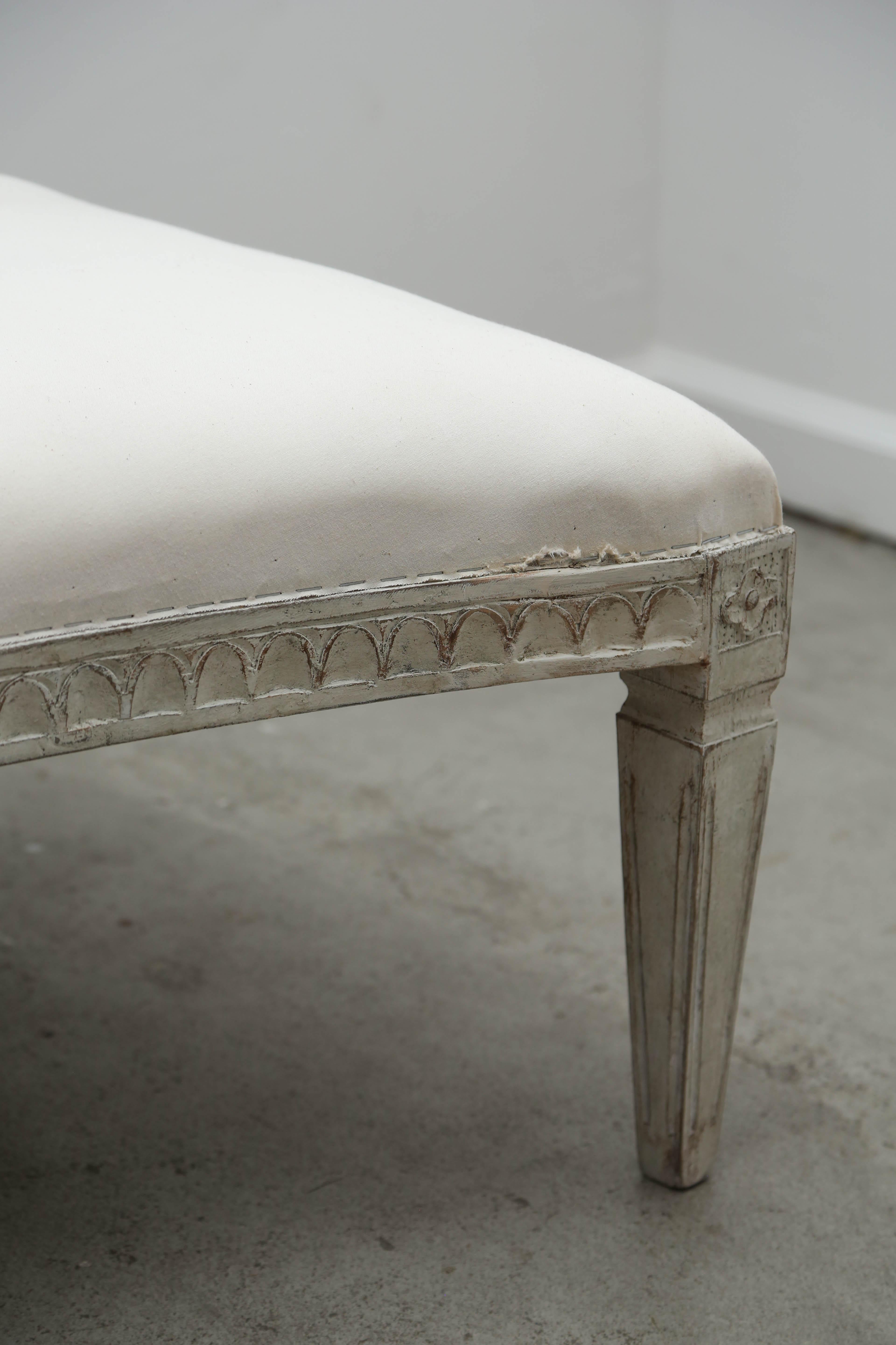 Antique Swedish Gustavian style distress painted curved bench in Swedish Gustavian white/greyish paint finish.
The border is carved with lamb tongue detail with a rosette carved at the top of each fluted leg.
Bench has a lovely graceful curved