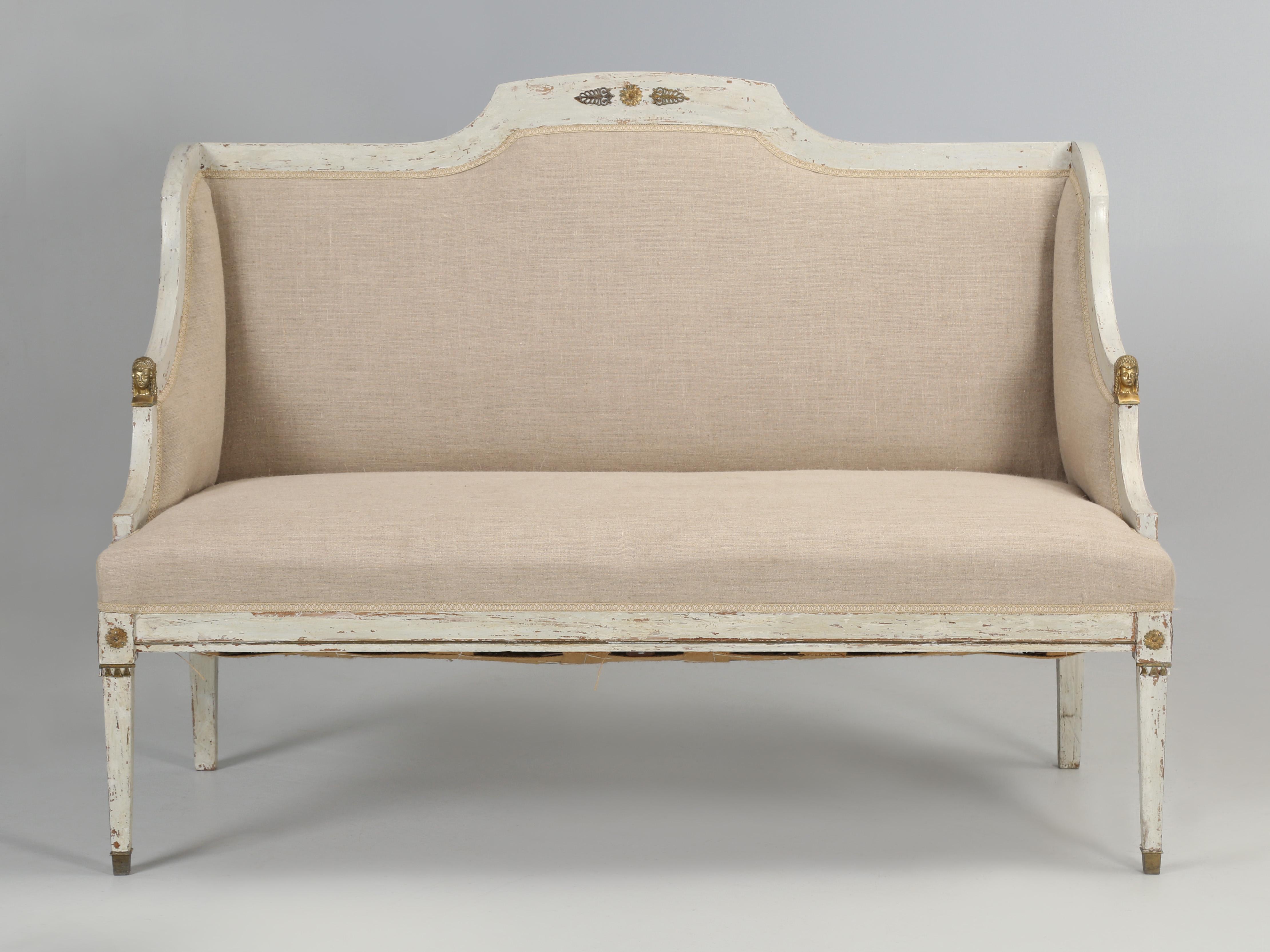 Antique Swedish Gustavian Settee in a classic putty grey paint that leans towards the blues. The linen fabric on our Gustavian settee appears to be fairly recent, although we have no personal knowledge of where it was reupholstered. Paint appears to