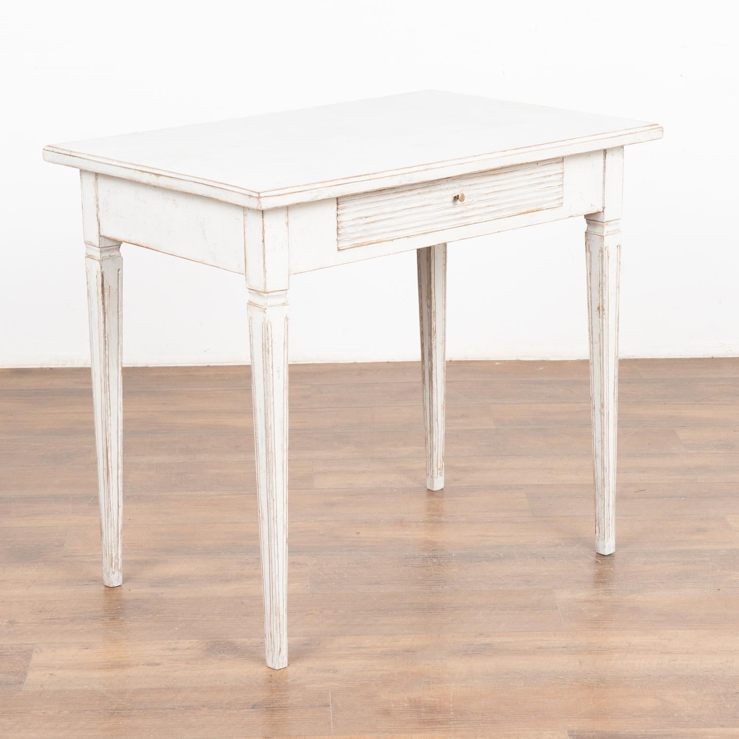 Antique Swedish Gustavian White Painted Side Table With Drawer.
Tapered legs and horizontal fluted carving along single drawer. May also serve as nightstand.
Restored, later professionally applied white painted layered finish lightly distressed to