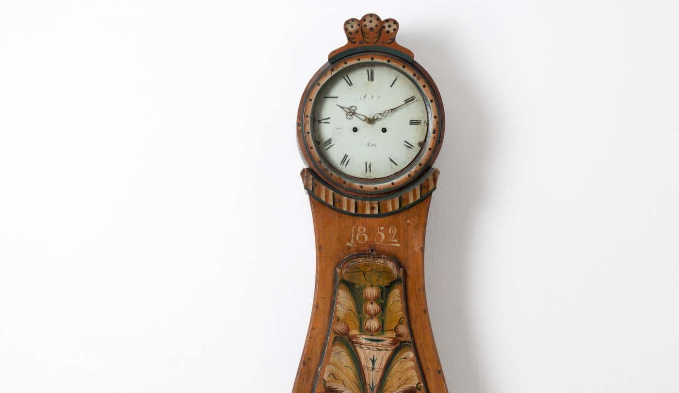 Antique Swedish long case clock with original decorative paint. The clock is from Hälsingland and has a simple model with rococo shapes. The paint is the original first layer which has remained untouched since 1852. It only has natural wear and an