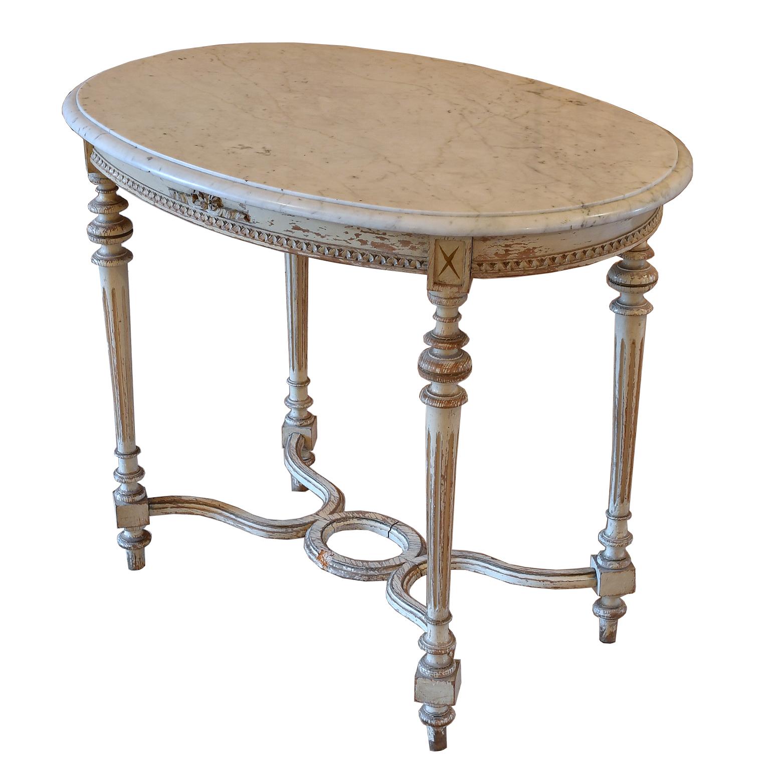 A lovely antique Louis XVI style salon table with painted Gustavian white/grey, distressed finish on wooden frame & white marble top with grey veining (likely Carrara marble) with ogee edge. Details include carved moldings and stretcher, with turned