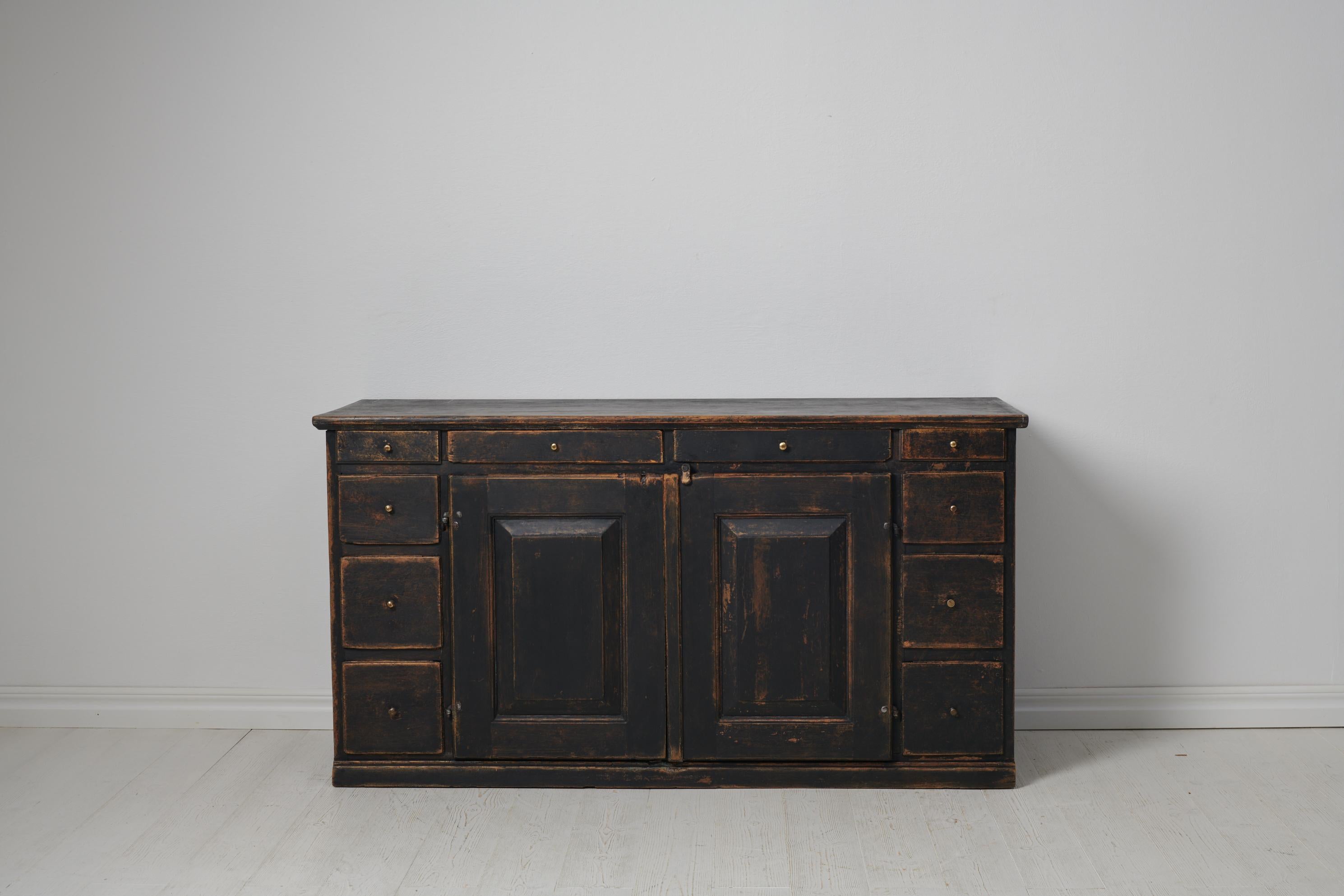 Swedish antique country sideboard from the 1800s. The sideboard is a genuine Swedish country sideboard made by hand in solid pine in northern Sweden around 1840. The sideboard is low and wide with double doors and 10 drawers in varying sizes. It has