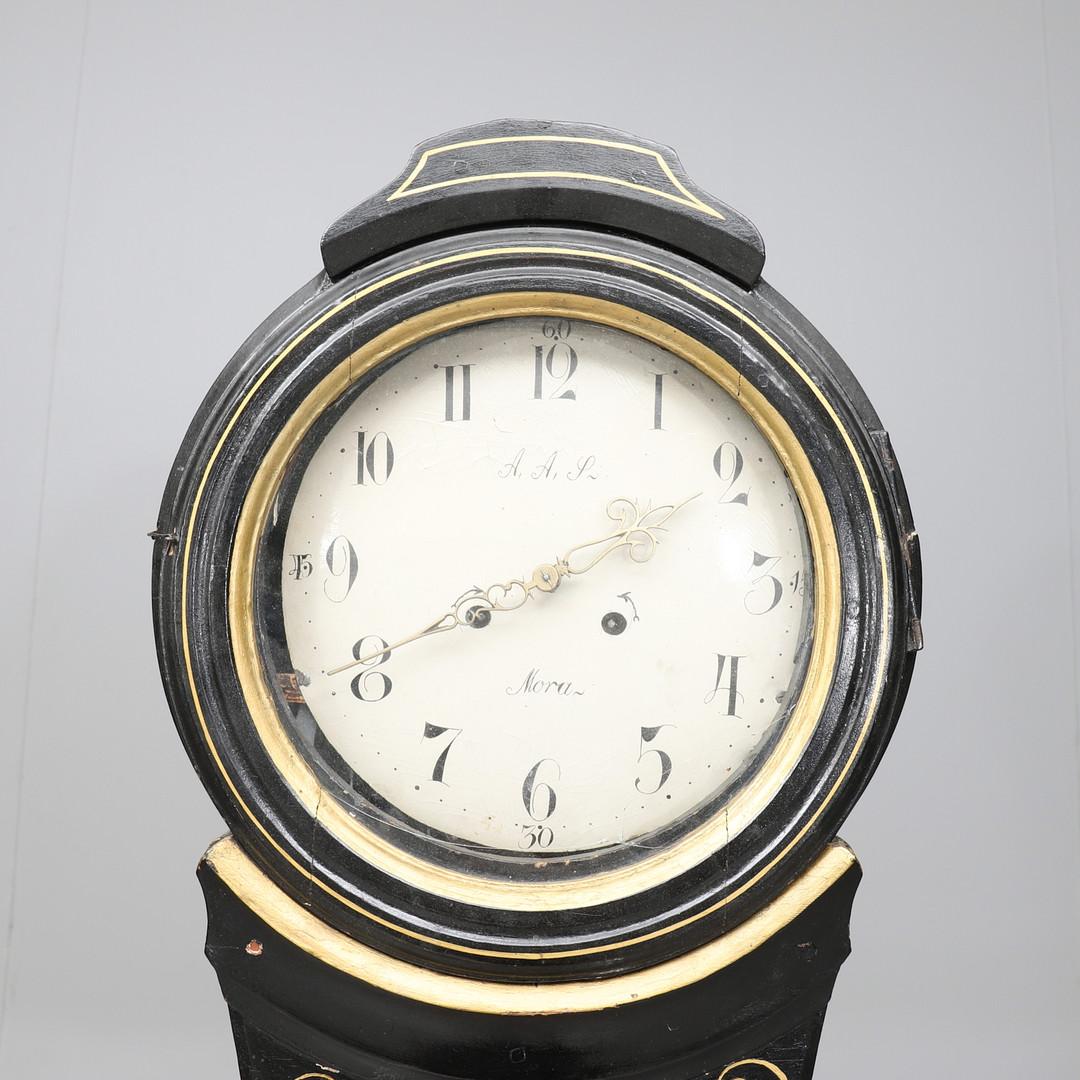 Antique Swedish mora clock from early 1800s in original black paint with hand painted gold designs and golden angel and decorative face. Measure: 206cm.

The clock body paint has the usual distressing/cracking and wood movement found in clocks of