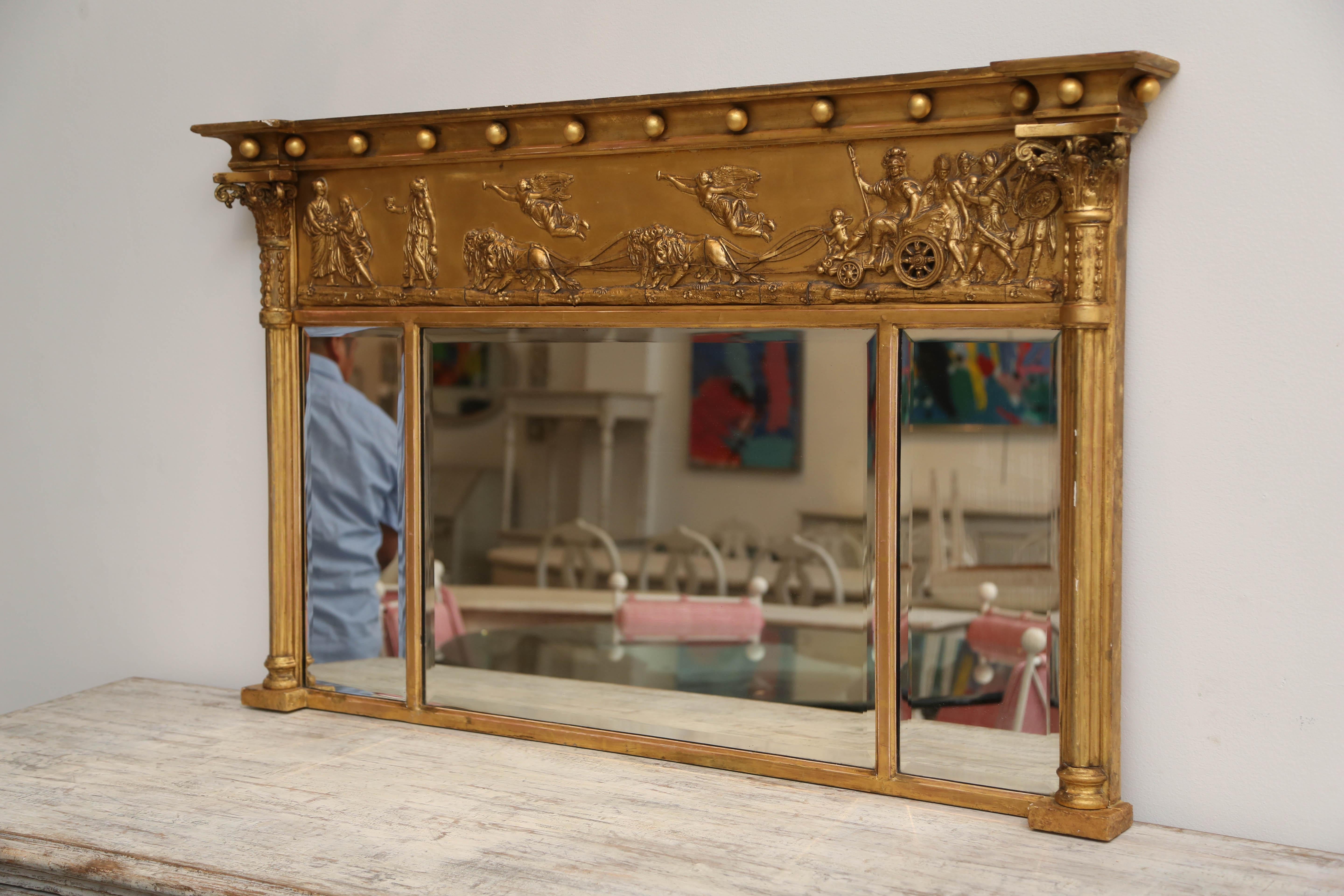 Antique Swedish neoclassic giltwood overmantel mirror. The classical top with a concave section and gilded balls above an apron with beautiful carvings of a warrior in his chariot pulled by lions and escorted by flying angels. The ends have half