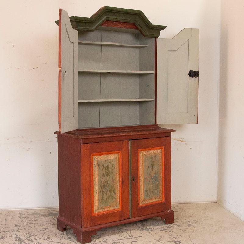 It is the beautiful original paint grown softer over time that creates the gentle appeal in this lovely cupboard from Sweden. The muted burgundy red background with soft green panels displaying delicate flowers were all hand painted in the late
