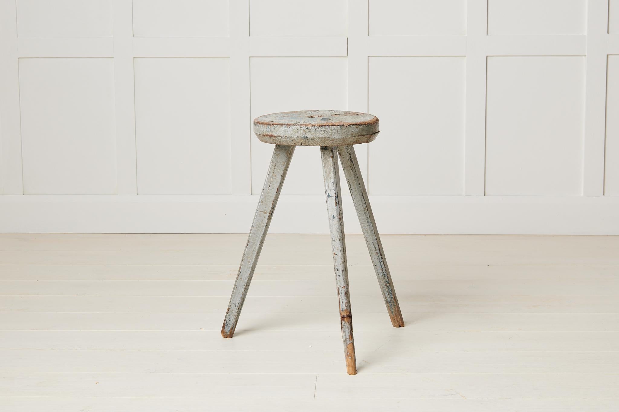 Antique Swedish rustic stool in folk art made with three legs. The stool has a round seat and is in its untouched original condition. The paint has become distressed with time and the resulting patina is full of rustic charm and character. This