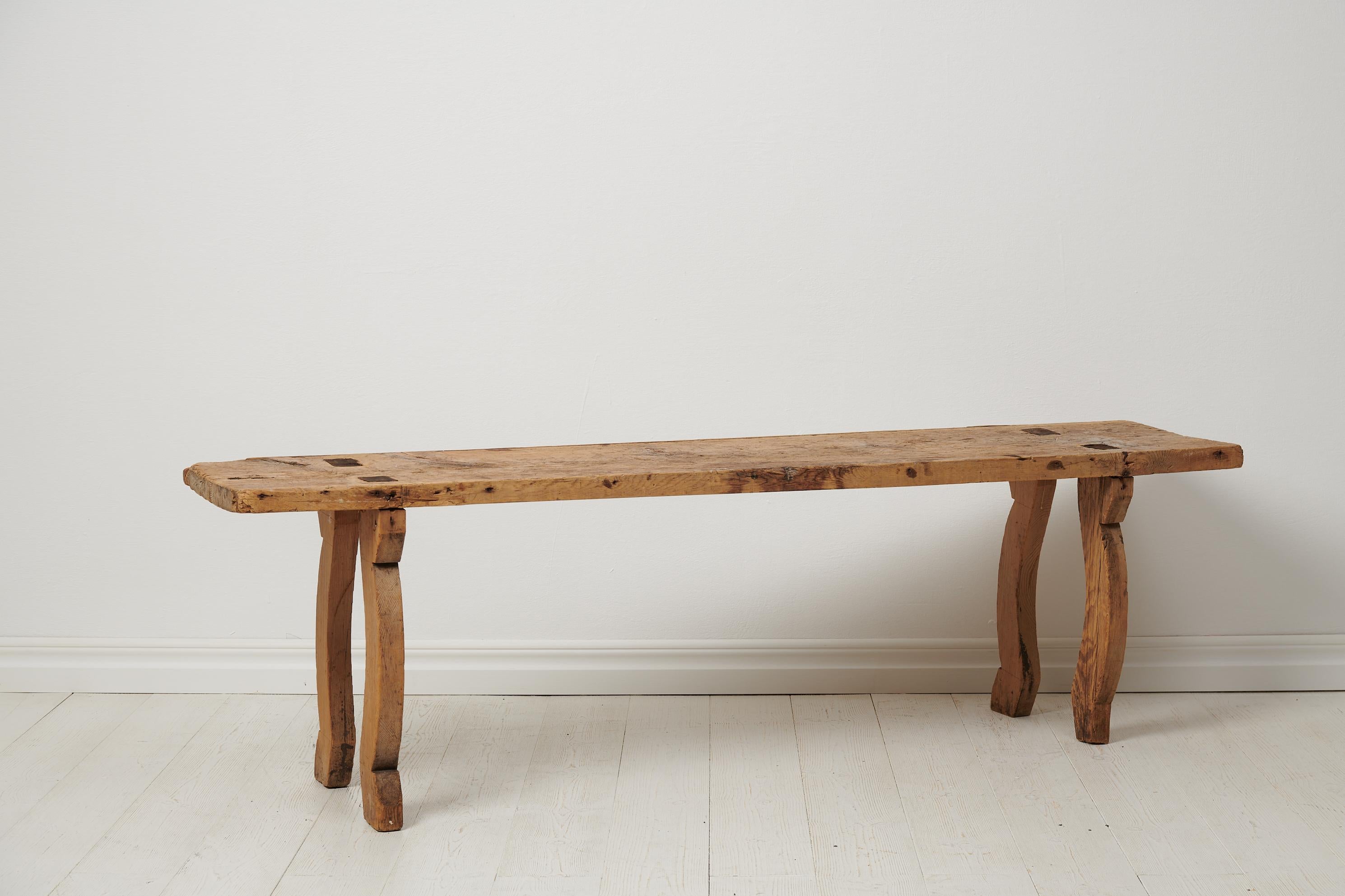 Antique primitive Swedish bench made in folk art. The bench is made by hand in solid pine around the year 1800 and has a rustic and authentically antique appearance. The bench has never been painted and was a utility furniture which was frequent