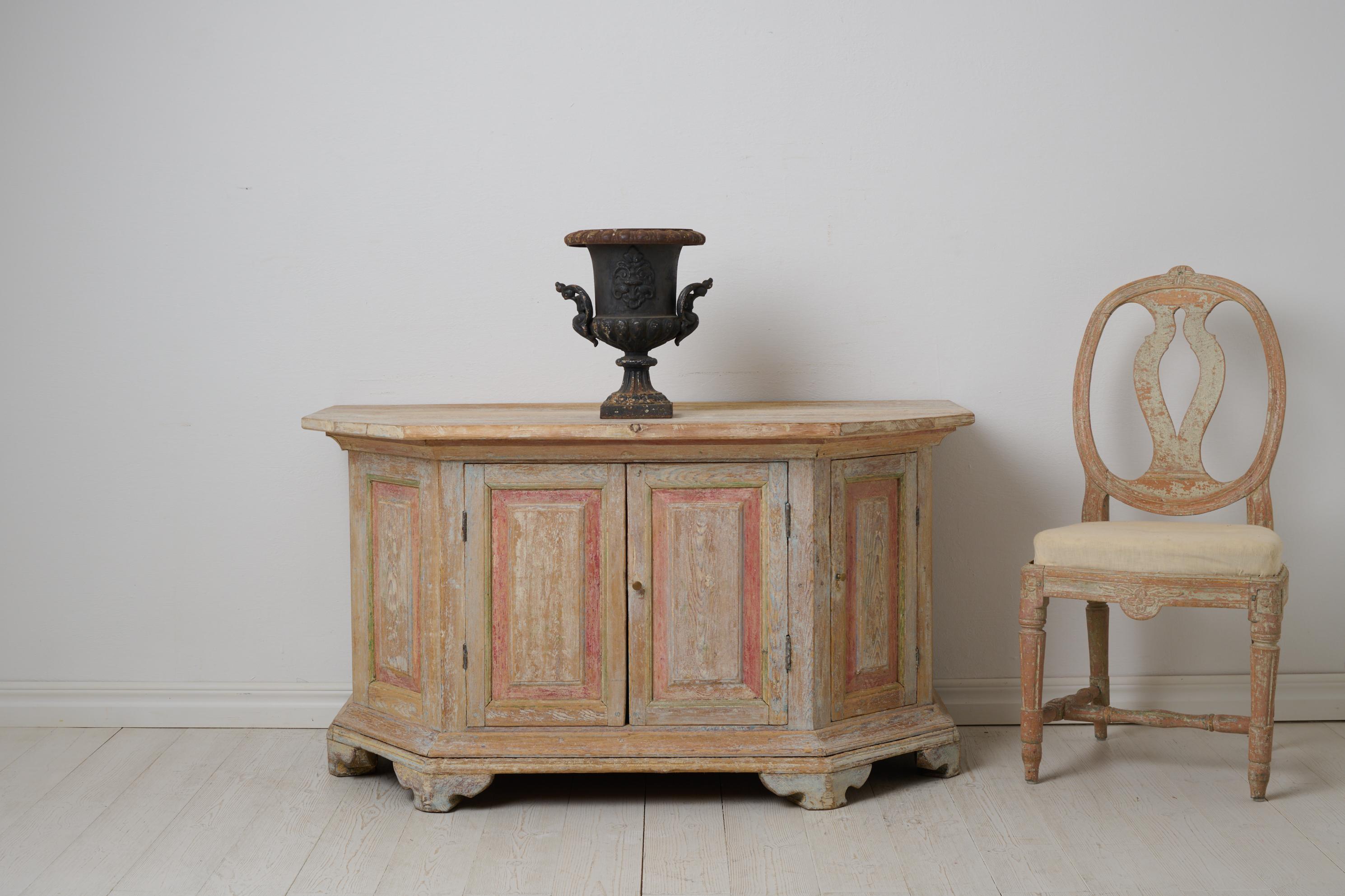Antica credenza svedese proveniente da Norrbotten, nel nord della Svezia, realizzata intorno al 1820. La credenza è bassa e larga e ha una forma insolita con angoli inclinati, che la rendono quasi arrotondata. Doppia porta al centro e porta singola