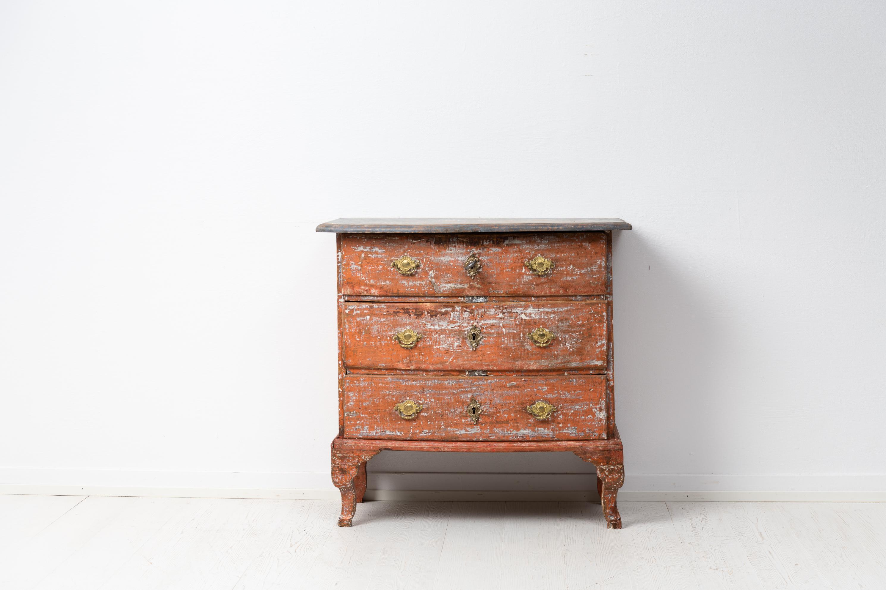 Small Swedish baroque bureau from around 1770. The bureau has three drawers and is made in painted pine which has been dry scraped by hand to the original paint. The original salmon-toned paint has patina and distress and the pine underneath shines
