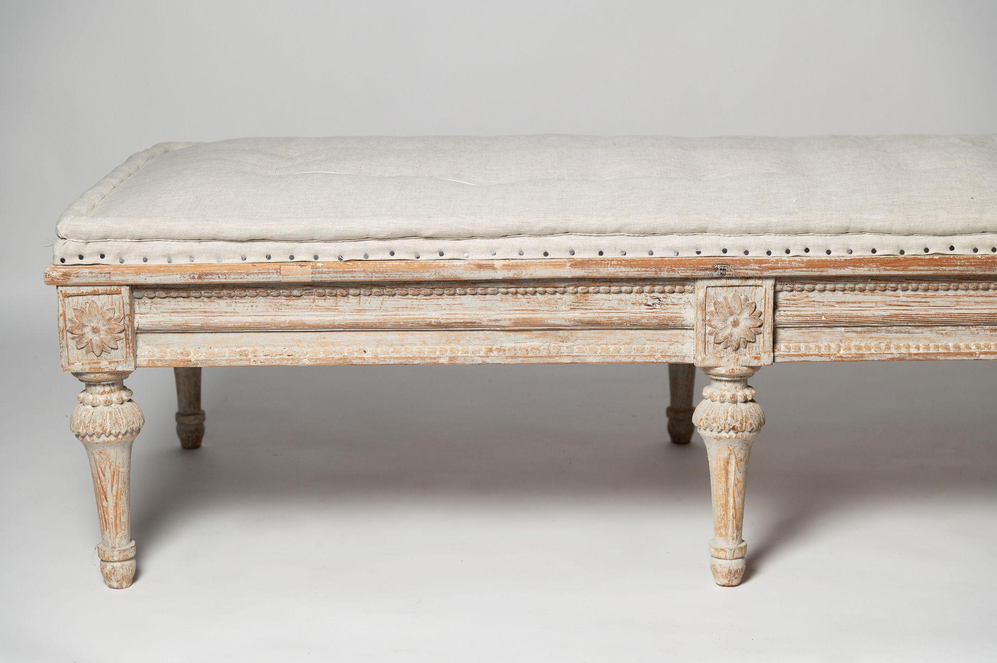 A period 18th Century c1780 Gustavian bench with wood carved decor to all four sides, later paint, recently upholstered in the traditional style in linen. A rare model.