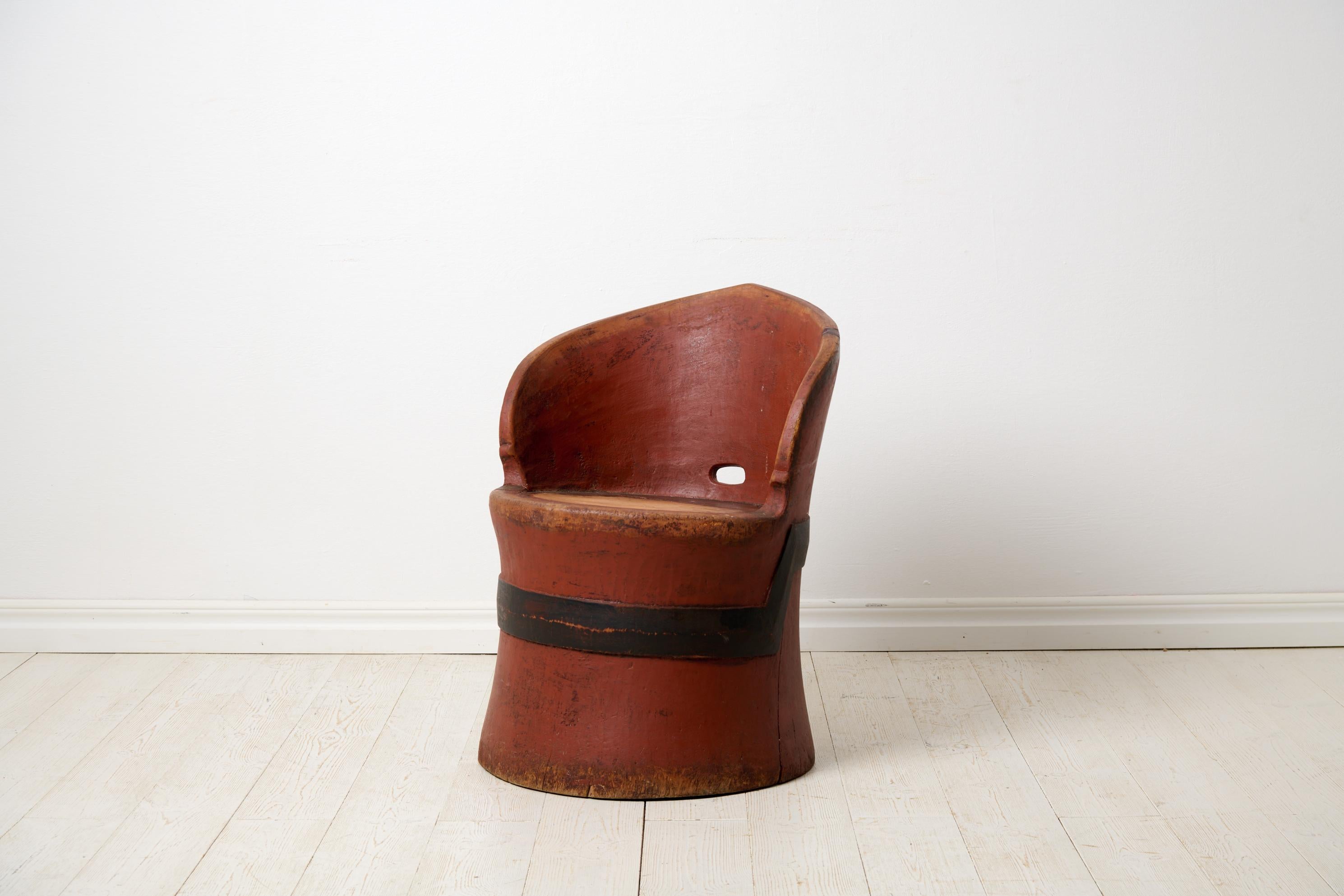 Antique Swedish stump chair with original red paint. The chair is a primitive furniture made by hand from one large, solid log of wood. The log has then been hollowed and shaped into the current form. Made from pine around the mid 1800s in Sweden.
