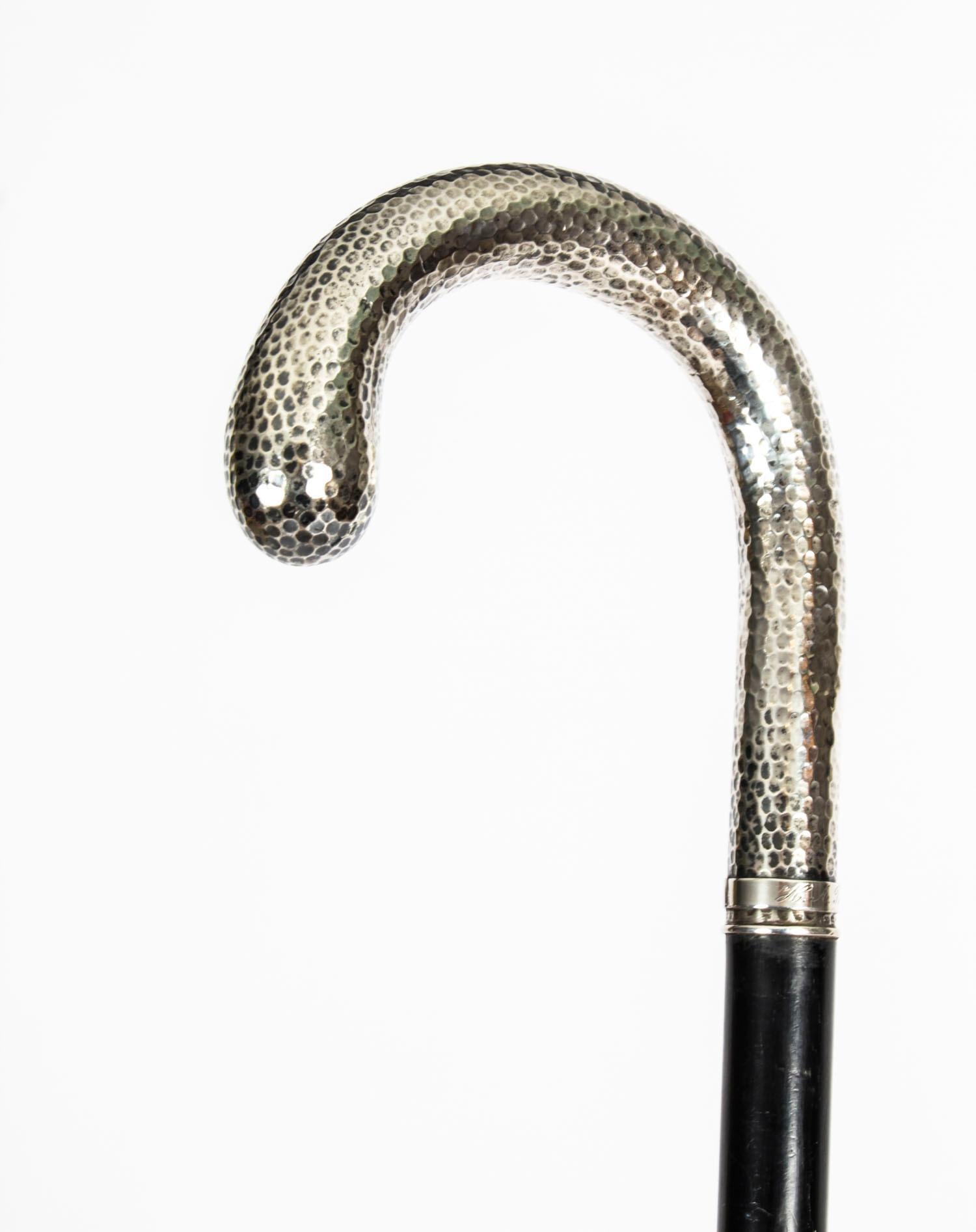 This is a fantastic antique Swedish gentleman's ebonised walking stick with a silver crook handle and bearing Swedish marks, circa 1910 in date.

It has a very decorative sterling silver curved planished crook handle with a plain band signed in