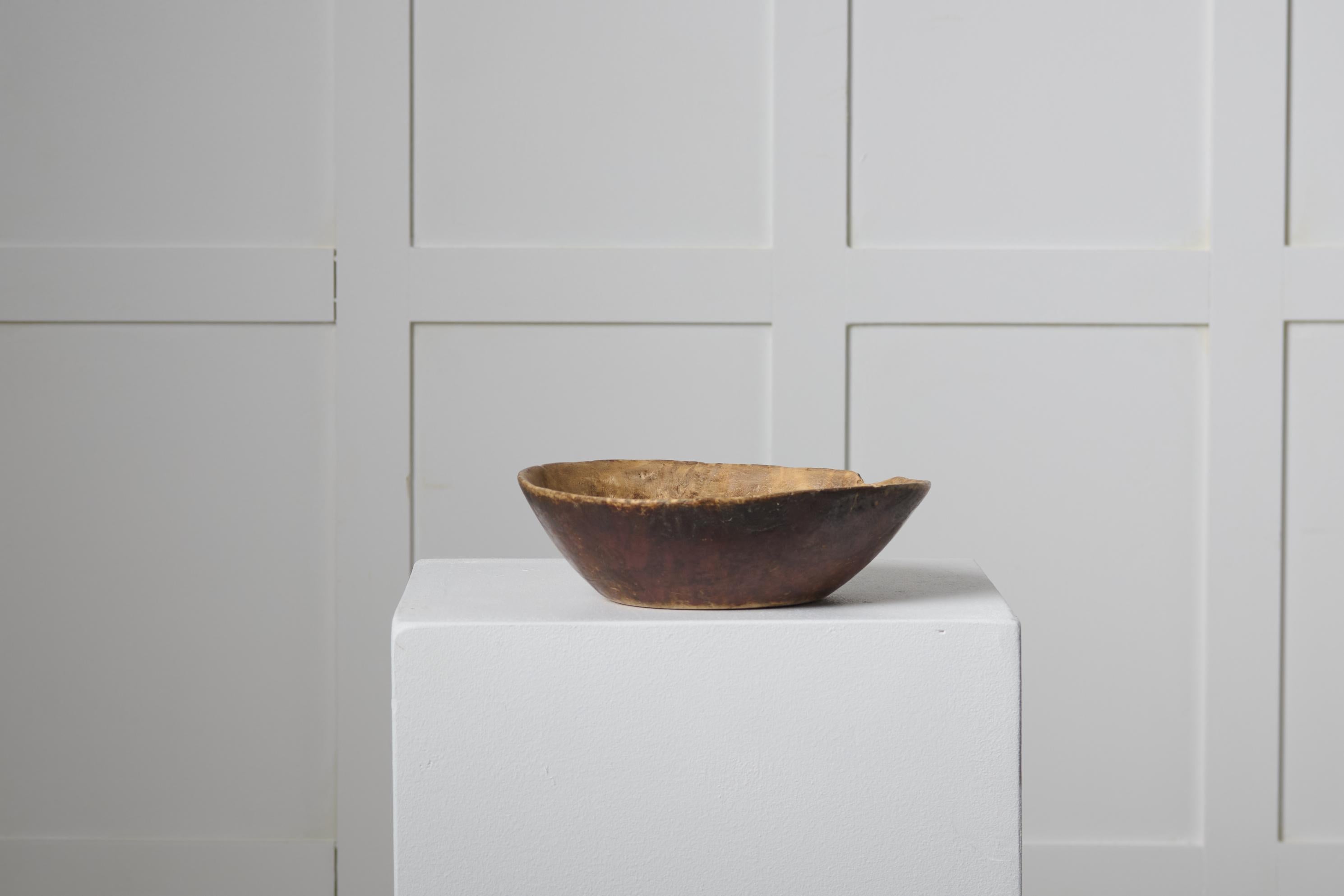 Antike schwedische Holzschale in gutem Vintage-Zustand mit authentischer Patina und Gebrauchsspuren. Die Schale hat eine runde Form und ist aus einem einzigen ausgehöhlten Stück Holz gefertigt. Die Außenseite ist original lackiert, während die