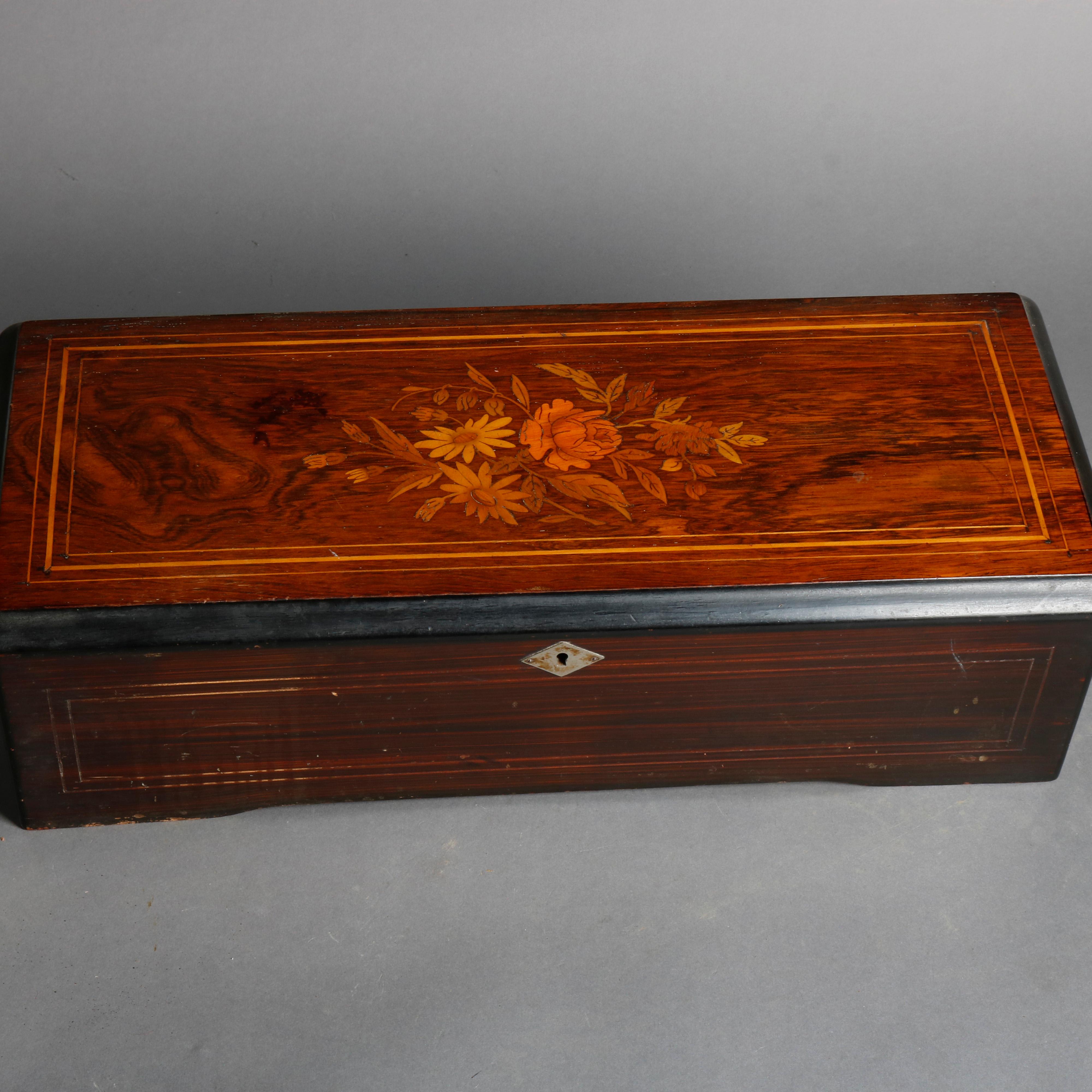 An antique Swiss 8-tune cylinder music box offers mahogany case with floral satinwood inlay mahogany top opening to reveal original tune card surmounting glass covered works, circa 1890

Measures: 5.75