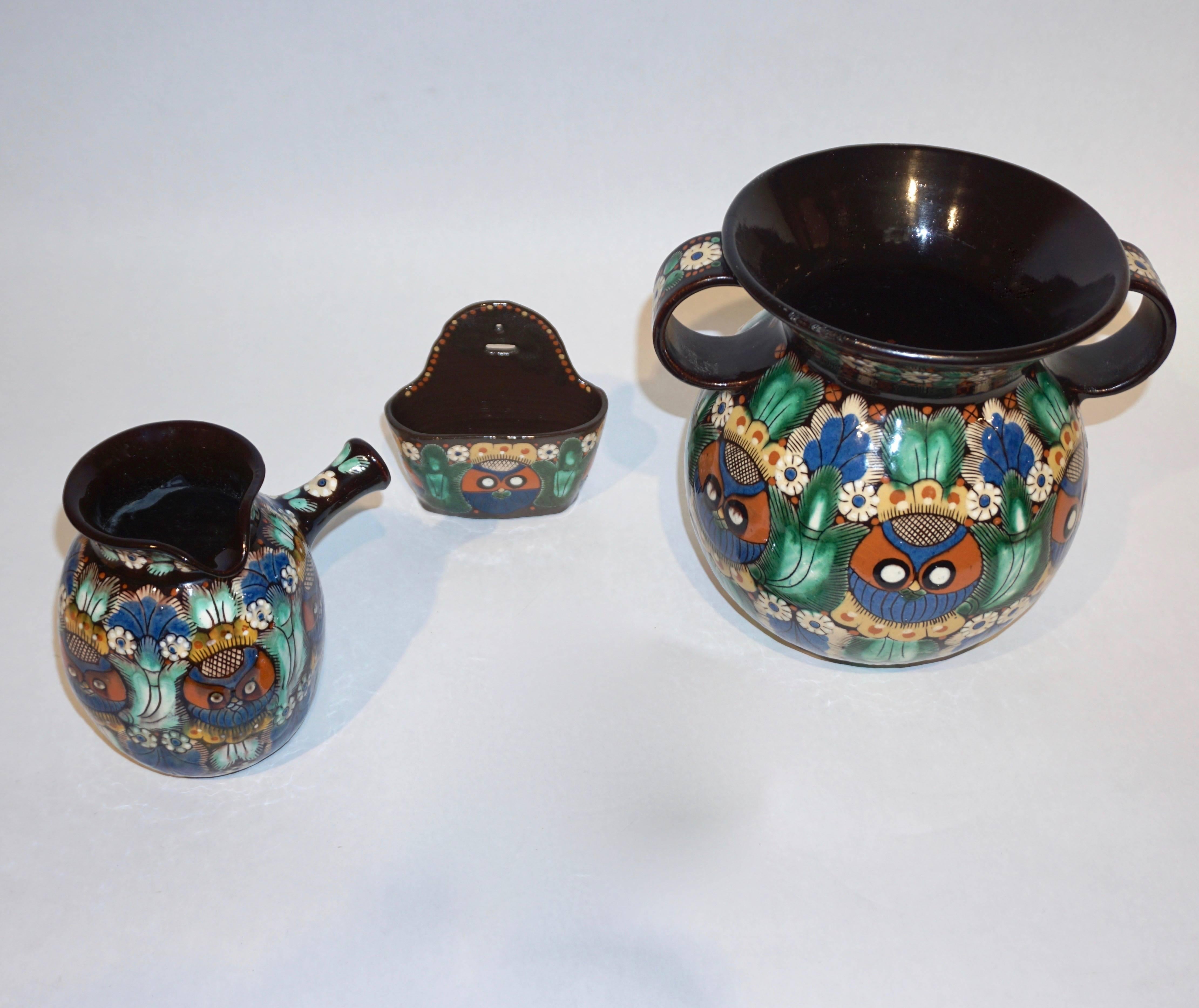 Early 20th century Arts and Crafts Majolica art pottery rare set of three pieces, made by the Swiss factory Thun/Thoune, circa 1910s. Each earthenware item, a two-handled vase, a jug and a note/match holder, entirely handcrafted and hand-painted, is