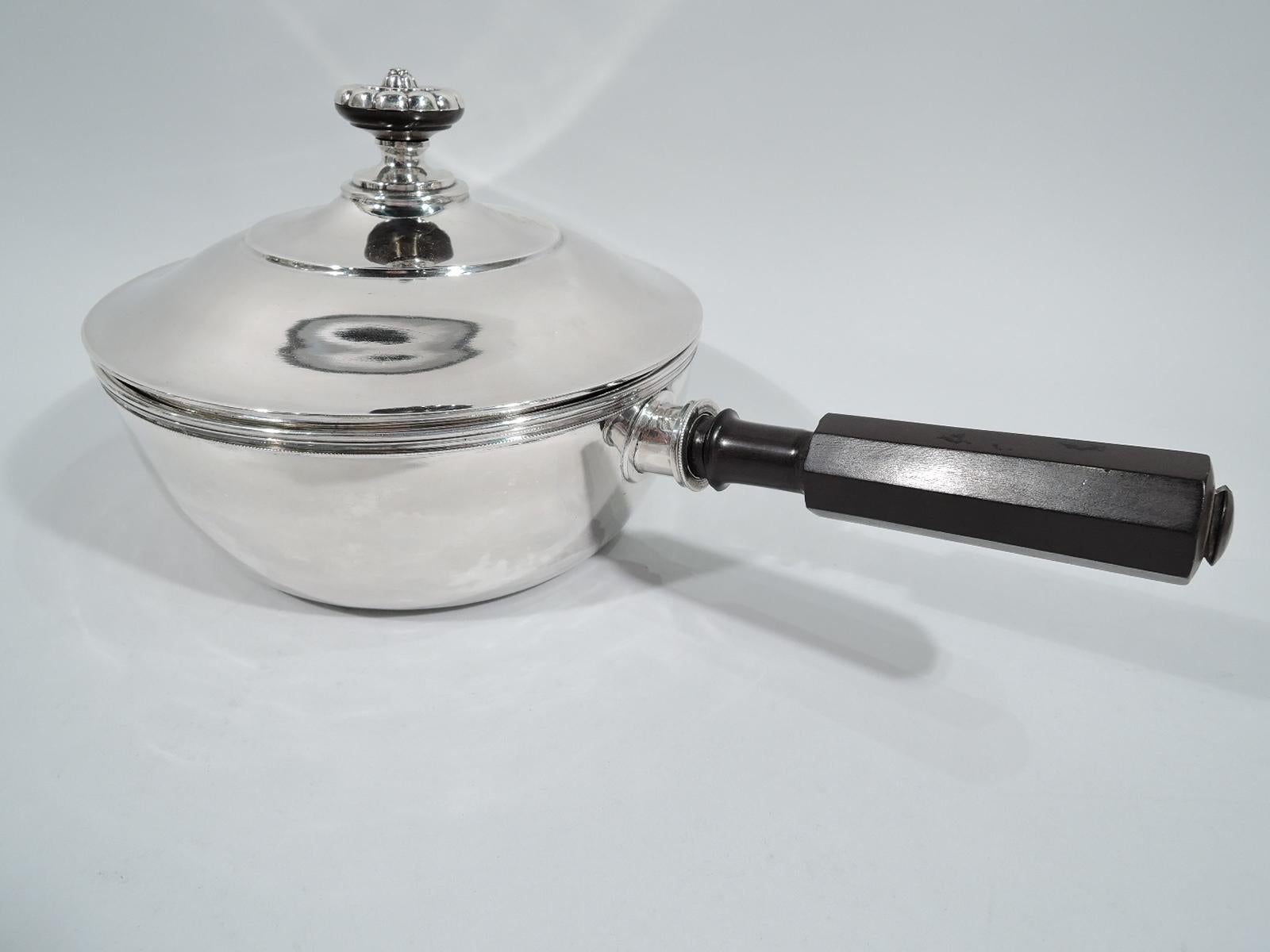 Swiss Biedermeier silver chafing dish, 19th century. Round with gently curved sides and molded rim. Handle faceted stained wood. Beading. Cover gently raised with naïve-style flower head finial. Marked.

Overall dimensions: H 6 1/2 x W 14 x D 8