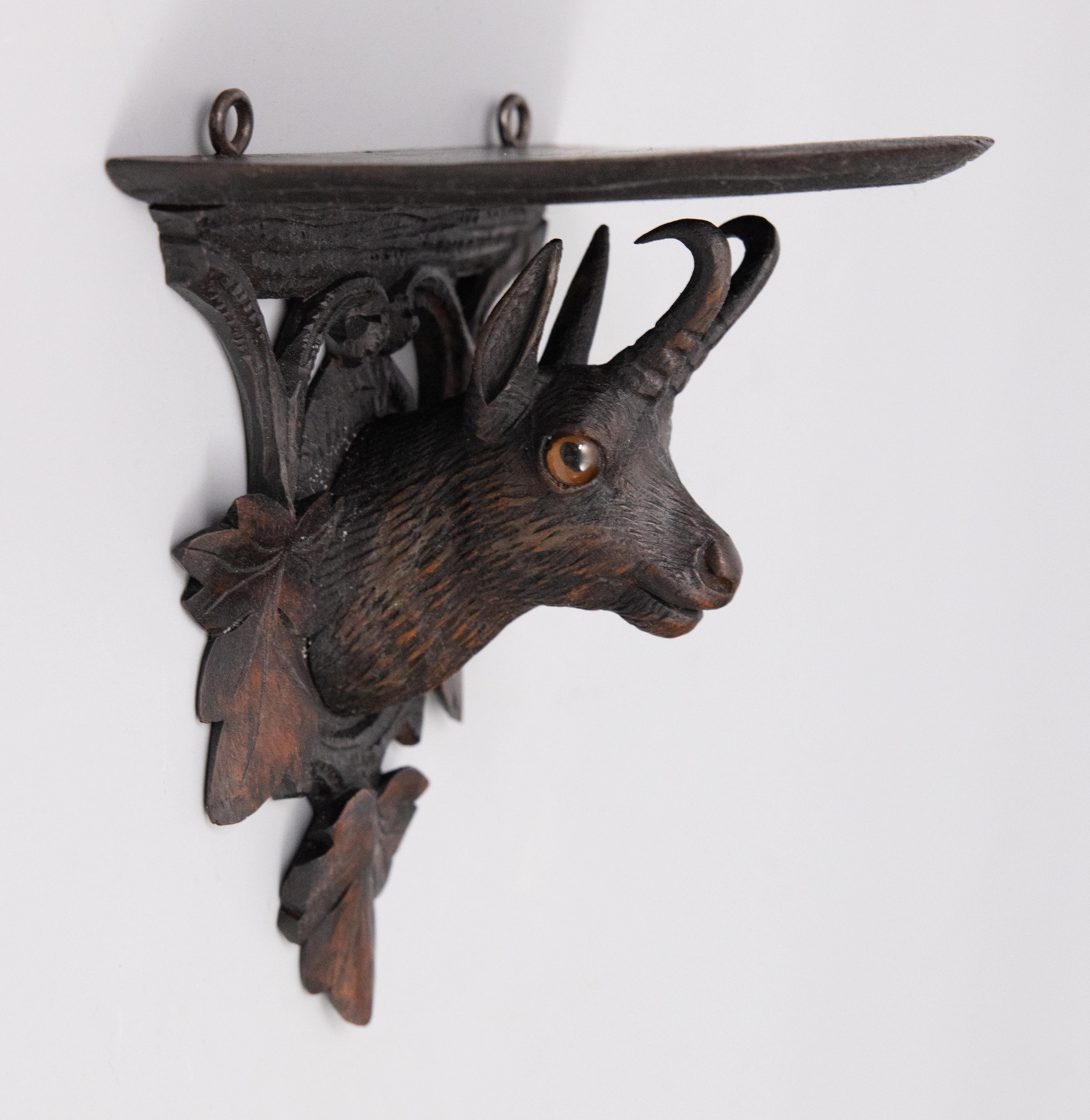 A superb antique Black Forest chamois or mountain goat wall bracket shelf hand carved in Switzerland, circa 1900. This fine bracket features a handsome chamois with glass eyes surrounded by intricately carved leaves. It's perfect for your rustic