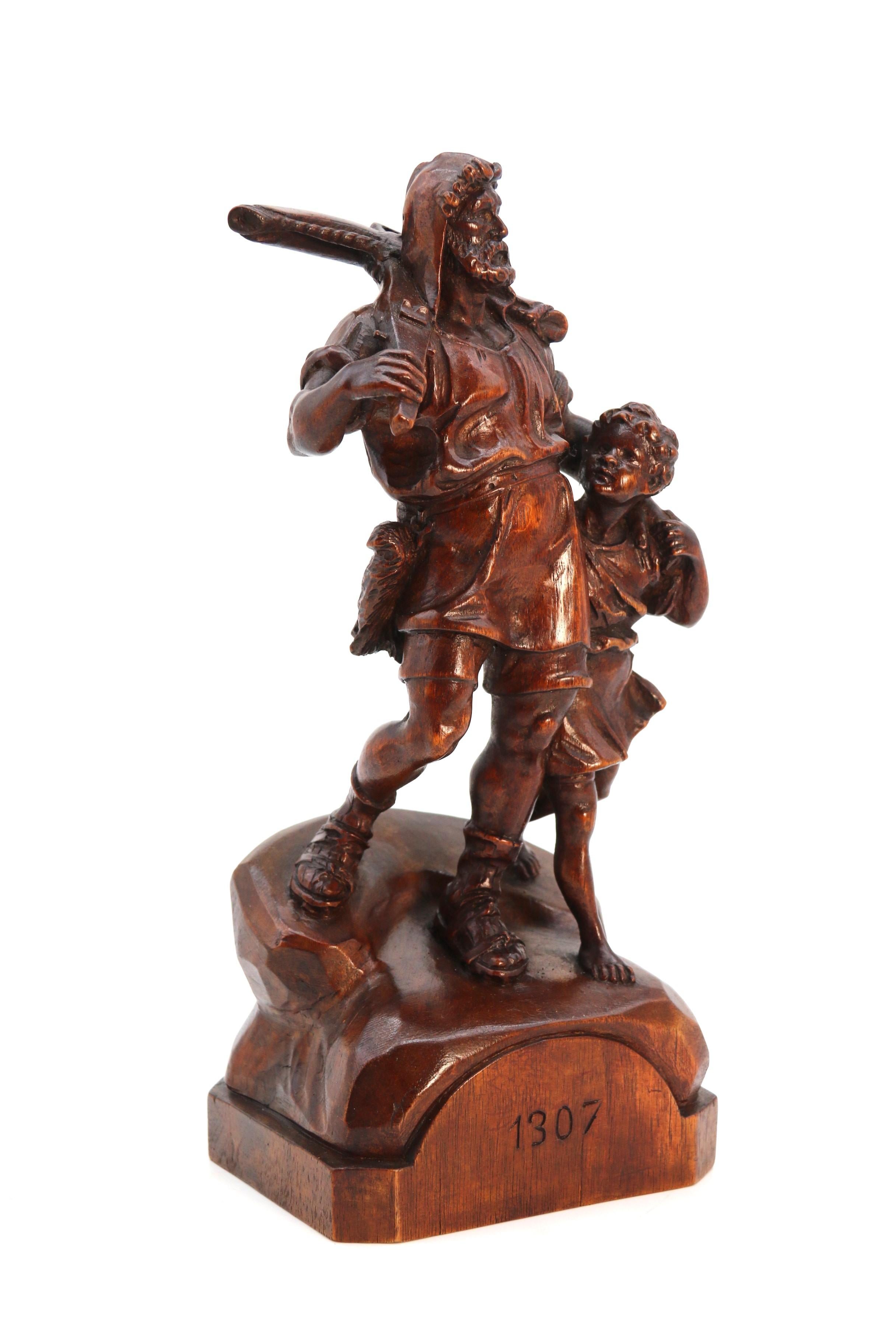 Questa scultura in legno di noce della Foresta Nera Svizzera di qualità superba raffigura la leggenda svizzera William Tell che cammina esultante verso casa a braccetto con suo figlio, con una grande balestra appoggiata sulla spalla e datata con