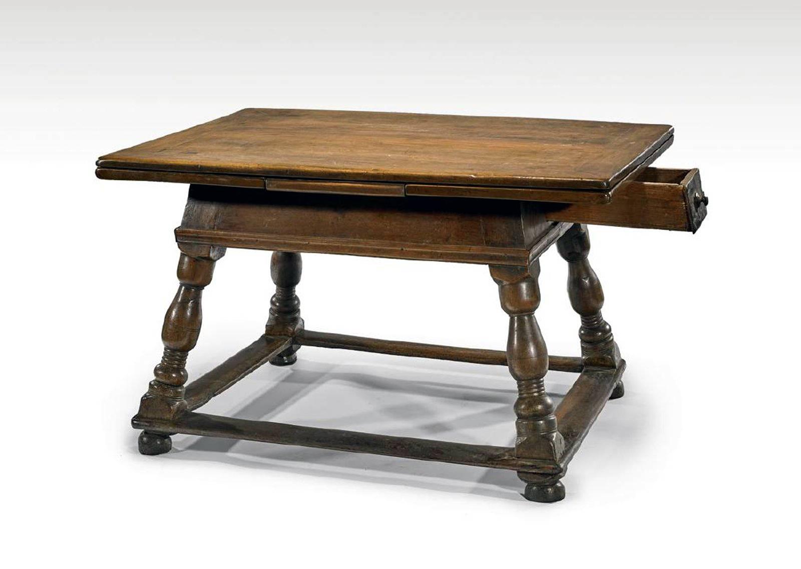 A fabulous antique Swiss wood tavern table circa late 17th to early 18th century, Known as Jogl table in Swiss Alps and German Bavarian region, the table features a carved rectangular top with a long frieze drawer to one side, two hidden draw-leaves