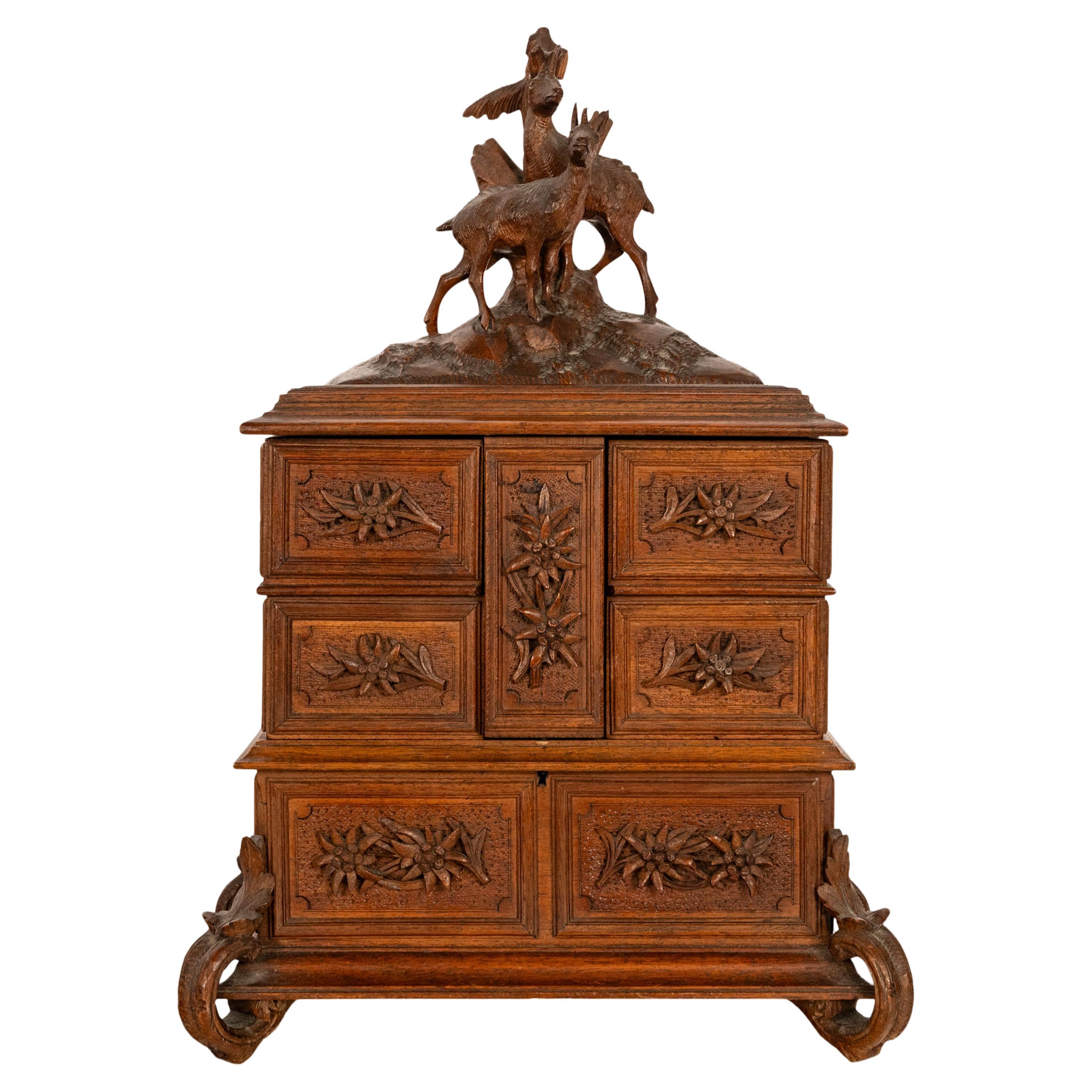 A fine antique carved walnut Black Forest jewelry casket, Brienz Switzerland, circa 1890.
The casket having a hinged lid carved with a pair of deer on a grassy outcrop and in front of a tree, below are four hinged storage boxes that swing outwards