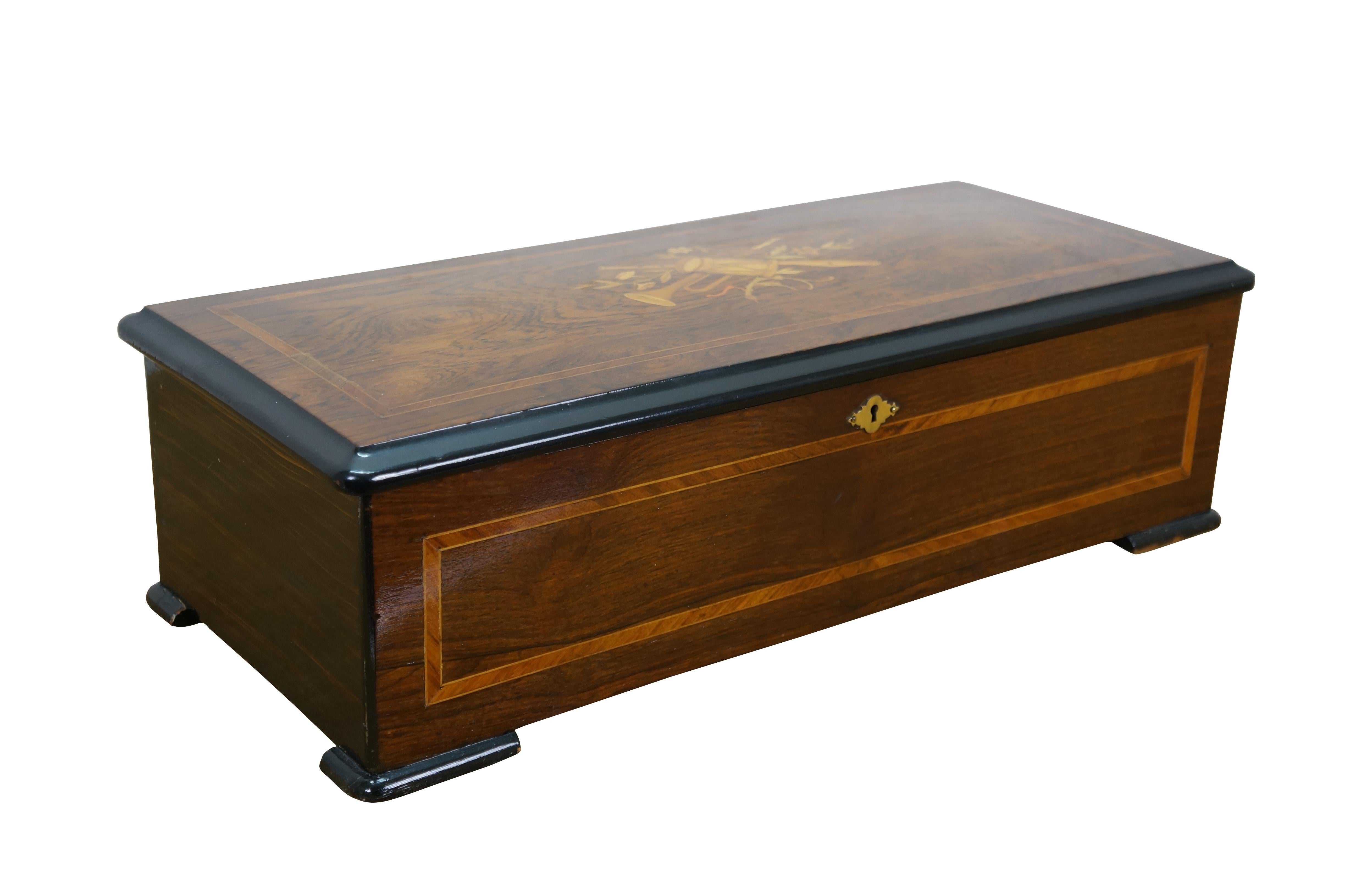 Exquisite late 19th century Swiss marquetry / parquetry cylinder music box capable of playing eight different tunes. Rectangular hardwood box with painted wood grain sides and inlaid front and top featuring a trio of instruments and flowers. Lock on