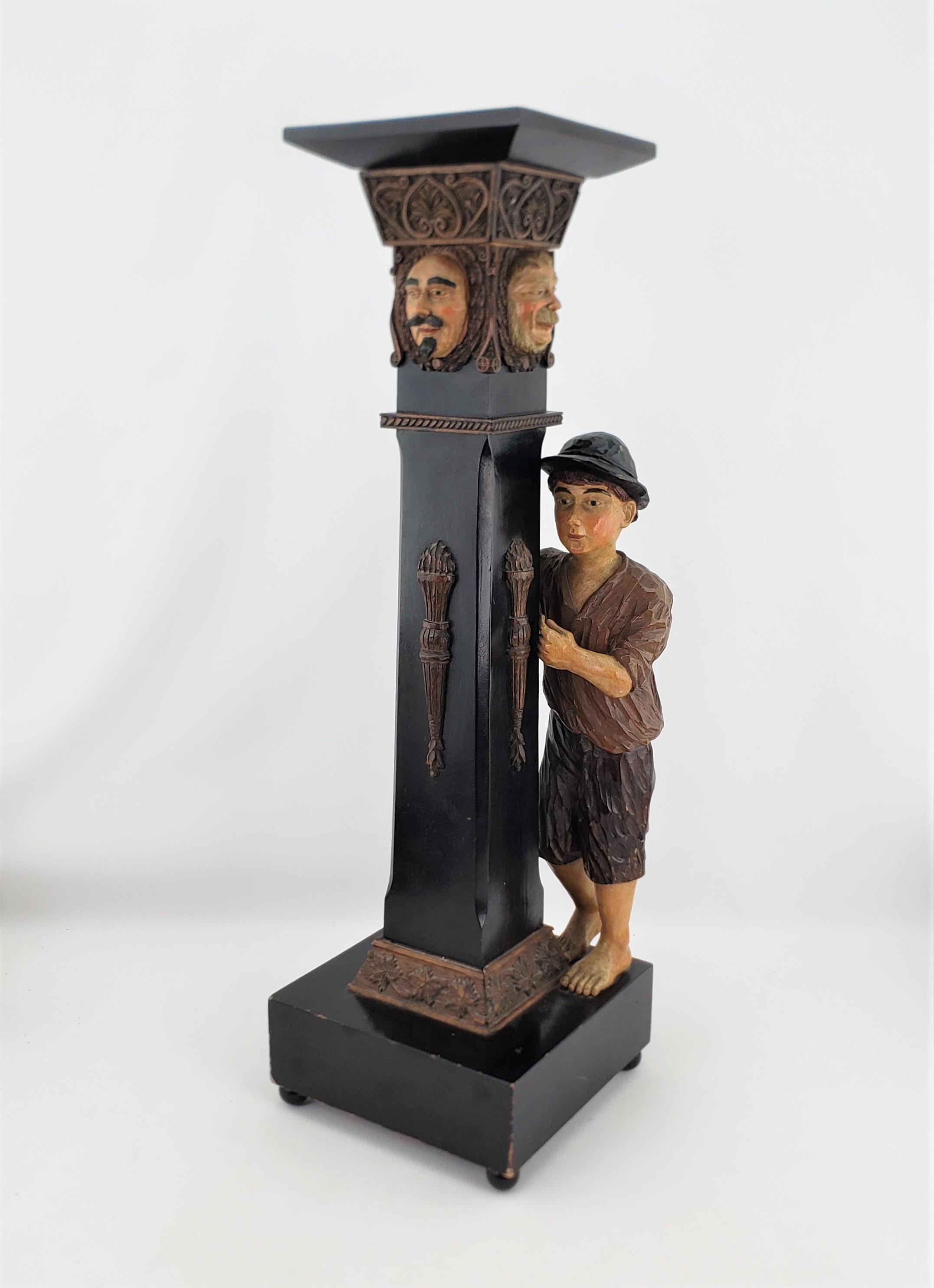 This antique hand-carved and polychromed painted pedestal is unsigned, but presumed to be either Swiss or German and date to approximately 1920 and done in the traditional, Black Forest style. The pedestal features a hand-carved young male peasant