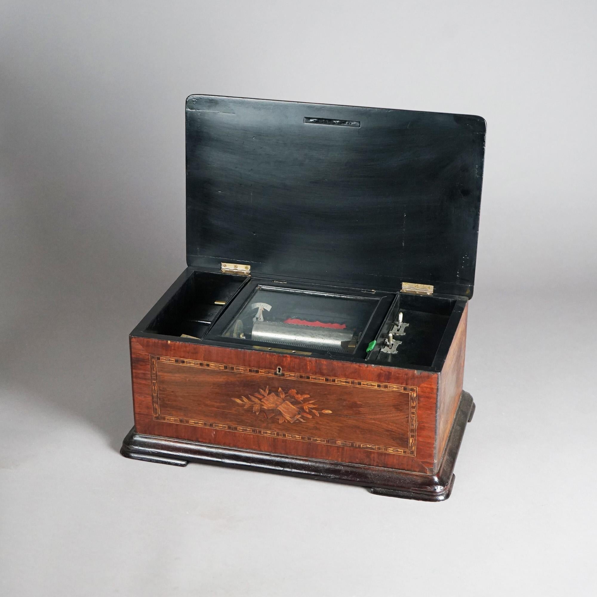 An antique six-tune Swiss music box offers rosewood construction with crossbanded top having floral marquetry decoration and opening to ebonized interior, 19th century

Measures- 8.5''H x 19.5''W x 11.75''D
