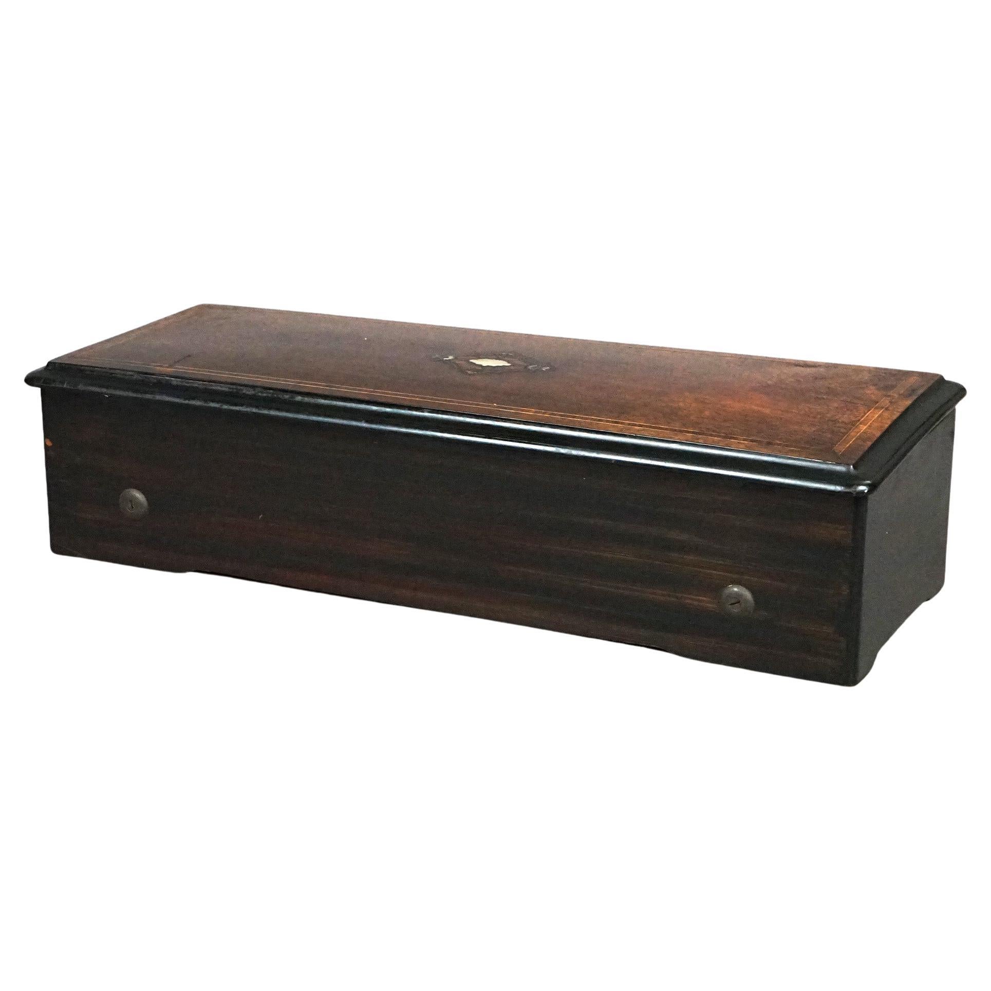 An antique Swiss standard twelve tune music box offers rosewood case with ebonized trimming and mother of pearl inlay, c1890

Measures- 13.25'' H x 23.25'' W x 8.75'' D.